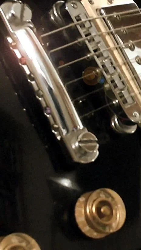Nahaufnahme einer Gibson E-Gitarre, man sieht die Brücke und die Regler.