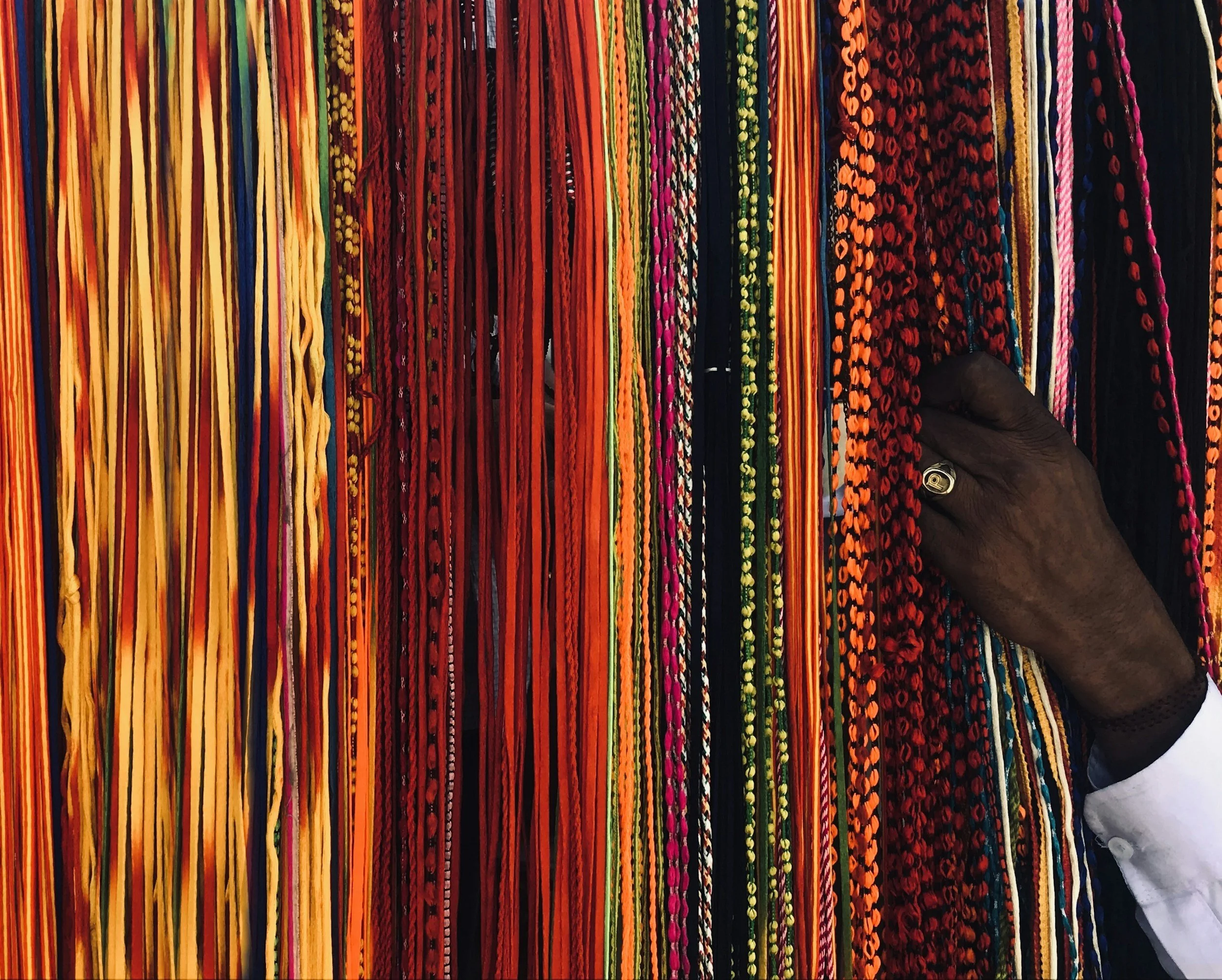 Colorful, intricately patterned fabric or yarns displayed in vertical strips.