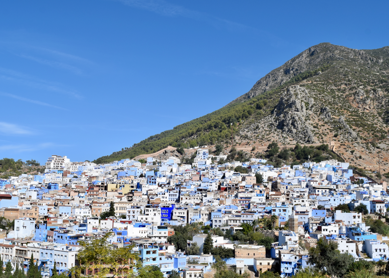 Blue-and-white buildings of Chefchaouen spread across the hillside beneath the Rif Mountains.