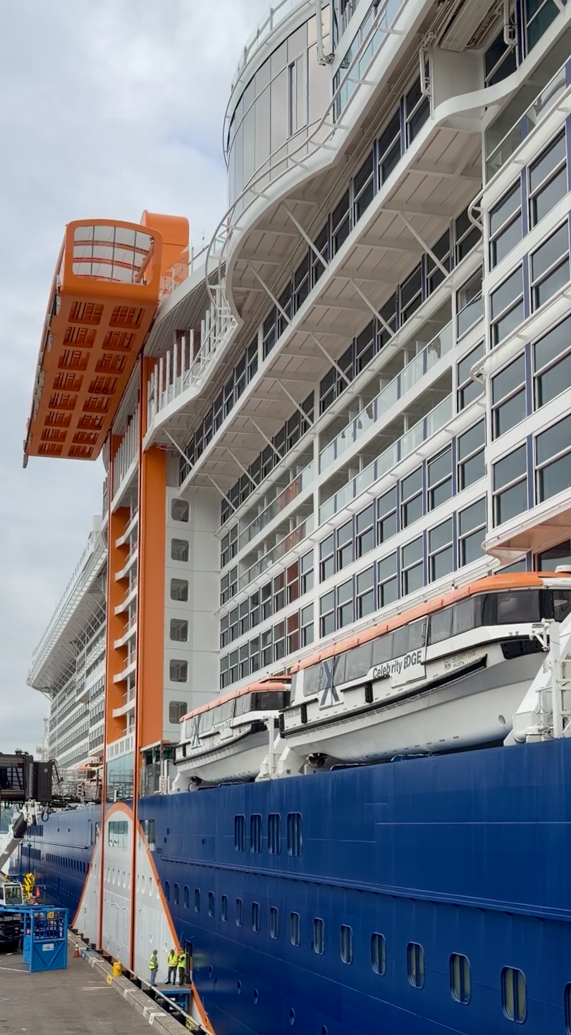 Celebrity Edge docked with its orange Magic Carpet platform extended along the side of the ship.