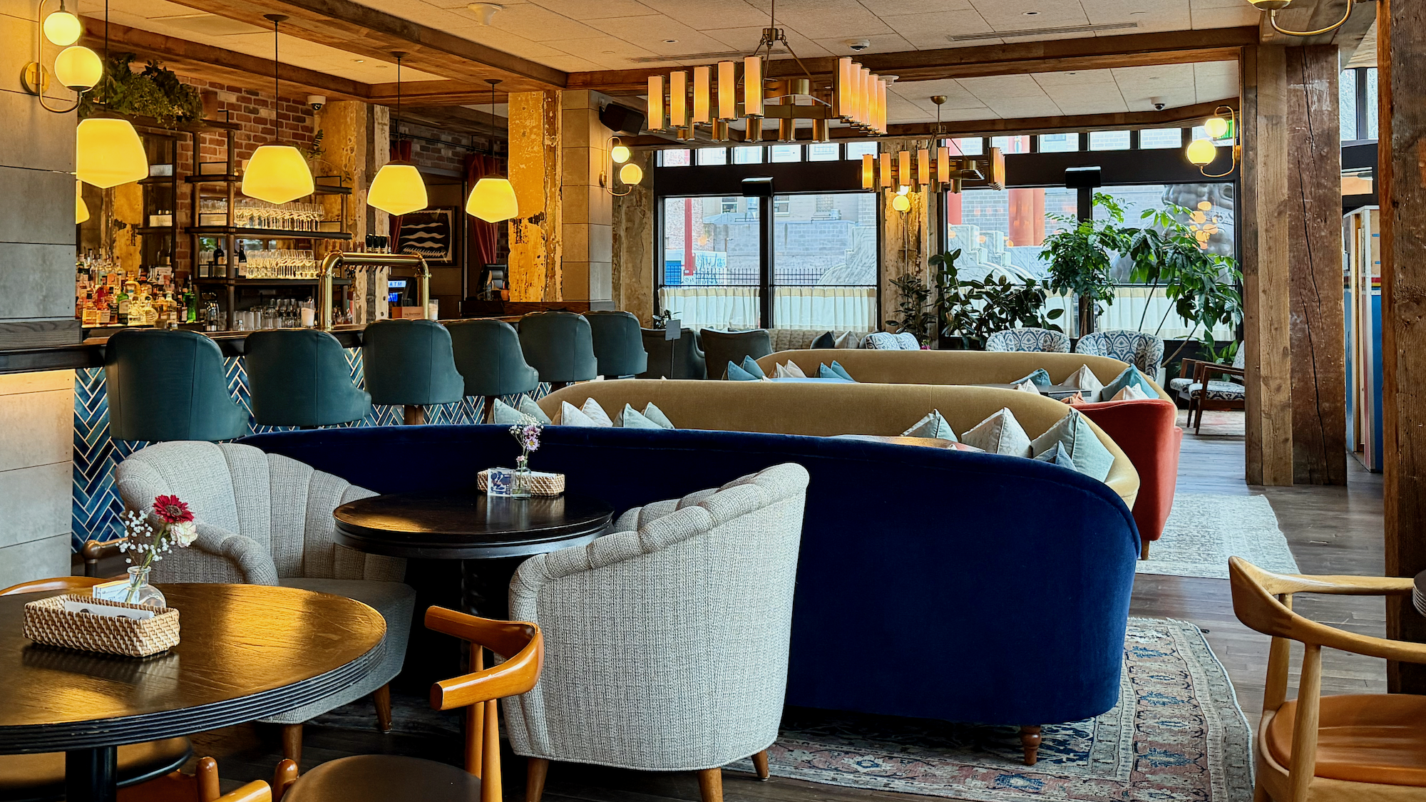 A stylish hotel lounge with sofas, armchairs, warm lighting, and large windows.