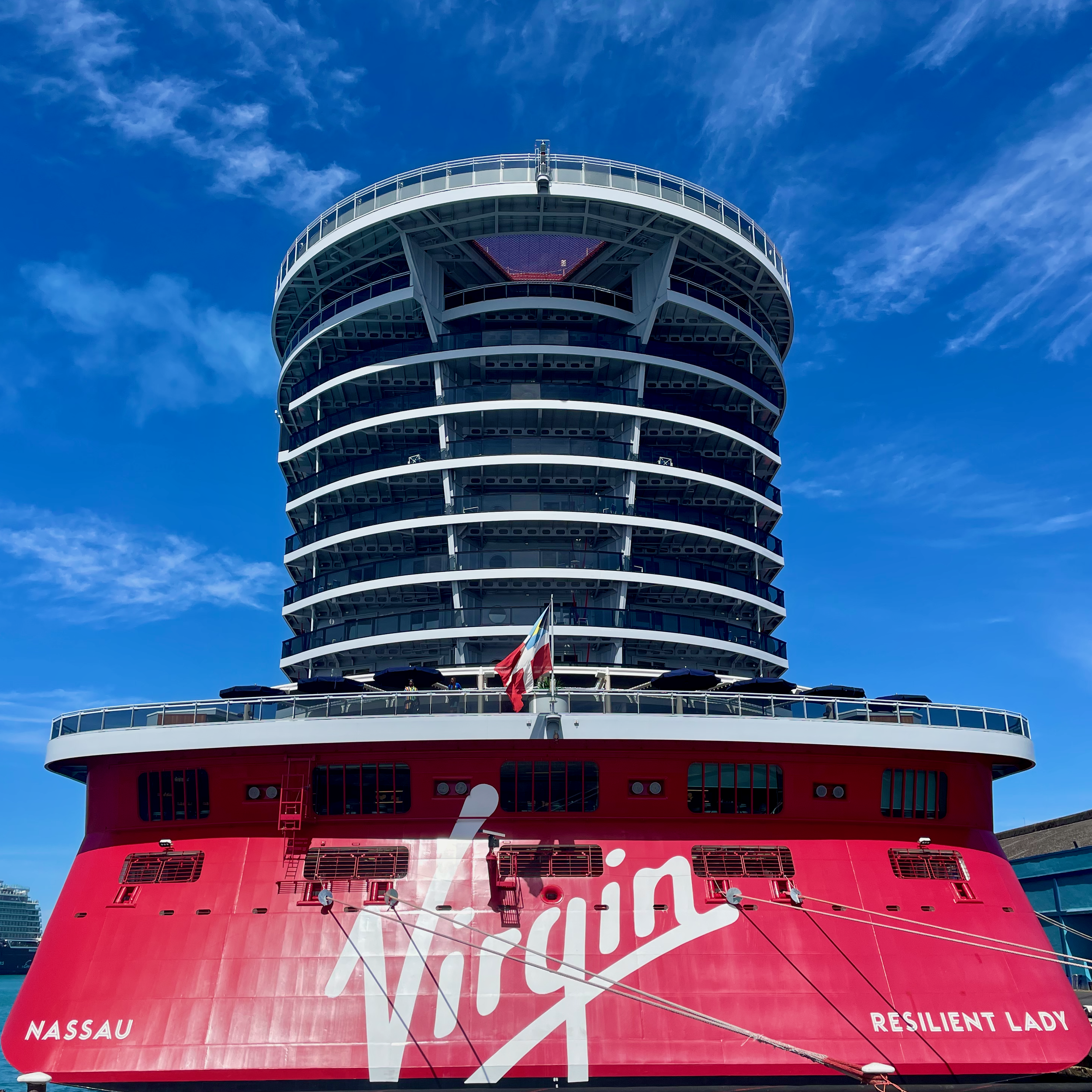 1. The red stern of Virgin Voyages’ Resilient Lady beneath a bright blue sky.
