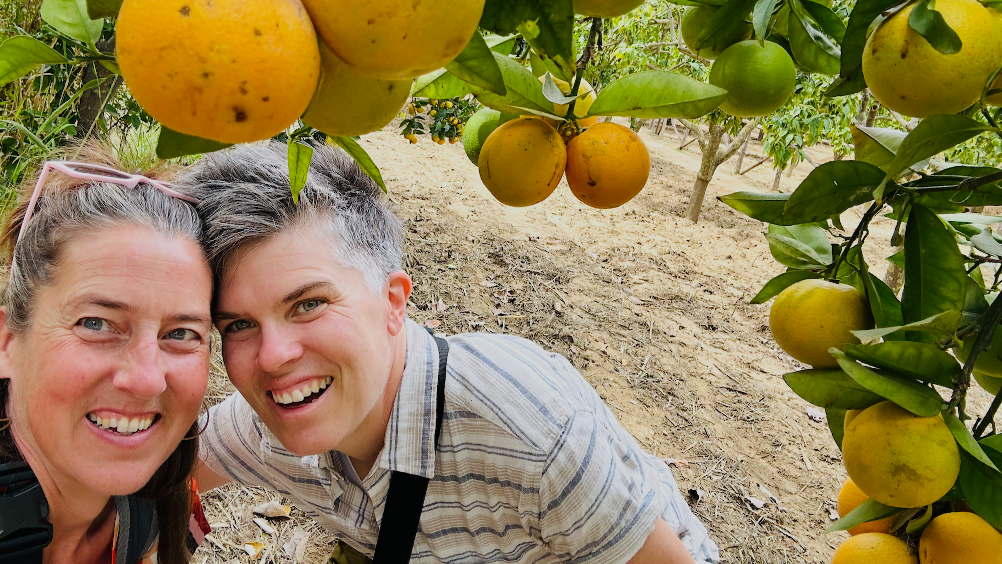 Briggs and Sonja smiling together beneath orange trees in Sicily.