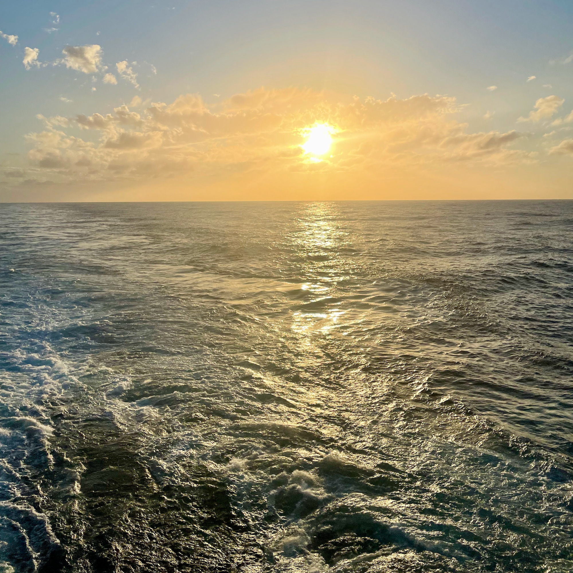 1. Sun setting over the open ocean behind the ship’s wake.