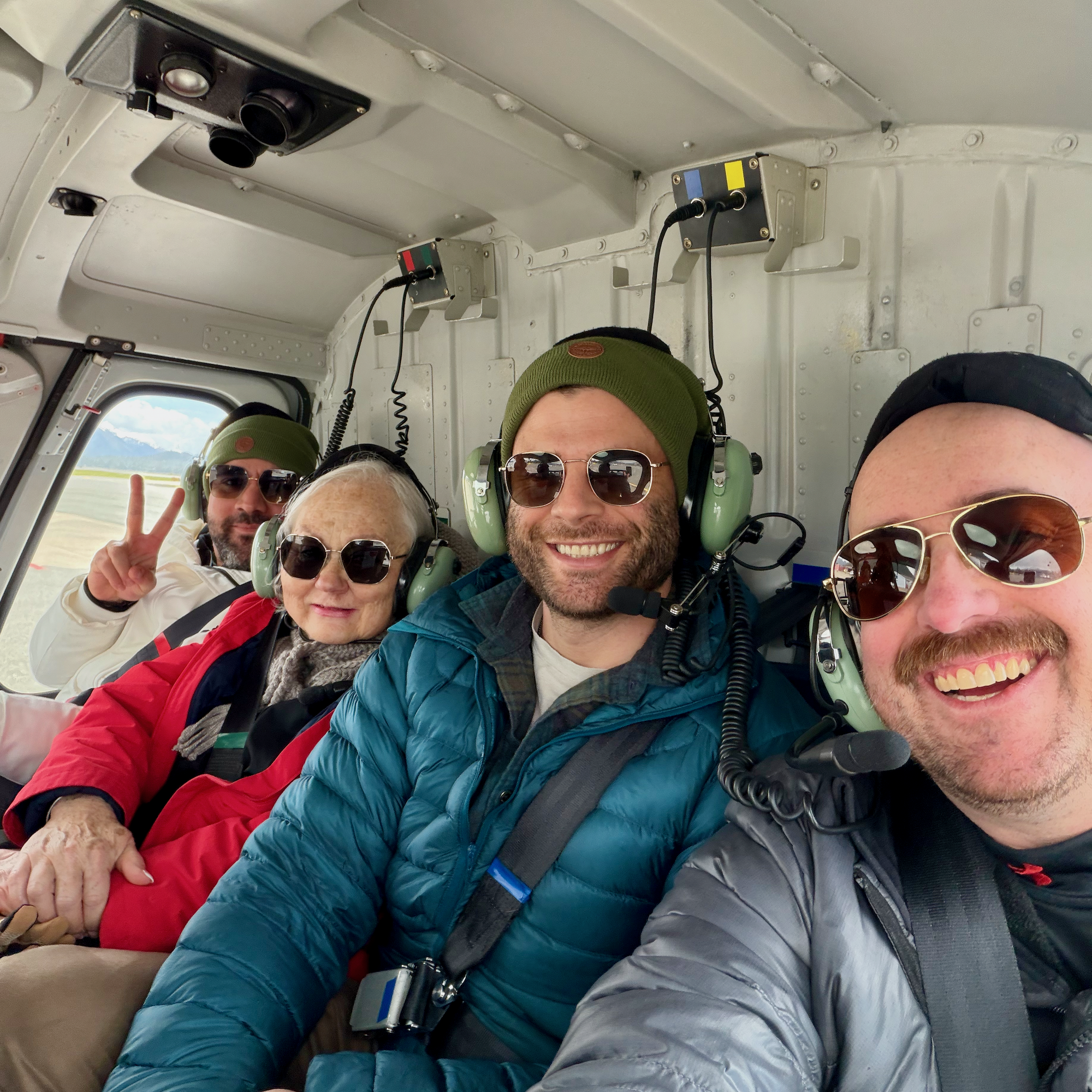 1. Four travelers wearing aviation headsets and smiling together inside a helicopter.