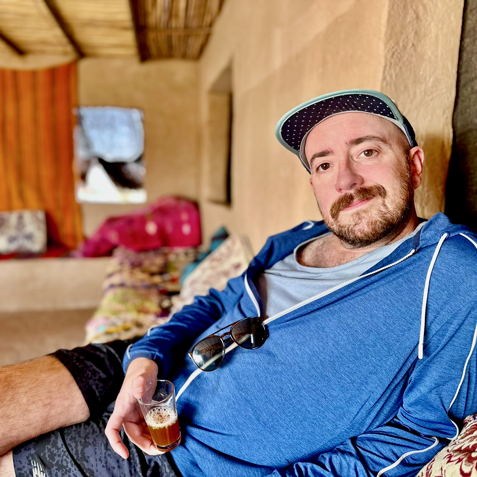 Travel advisor Michael Cole-Schwartz seated indoors, holding a cup of tea, and smiling at the camera.