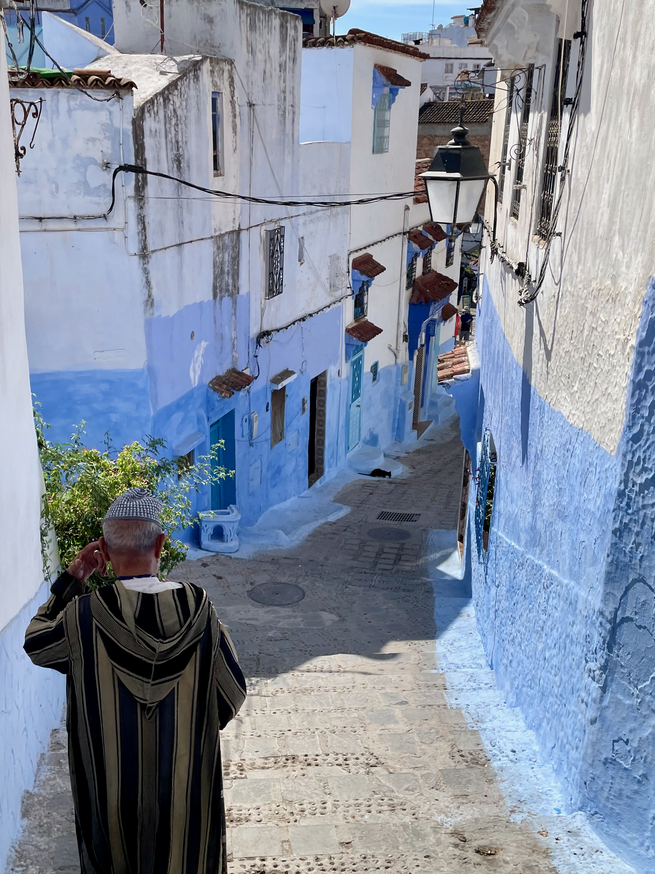A narrow blue-painted street descending through a hillside town in Morocco.