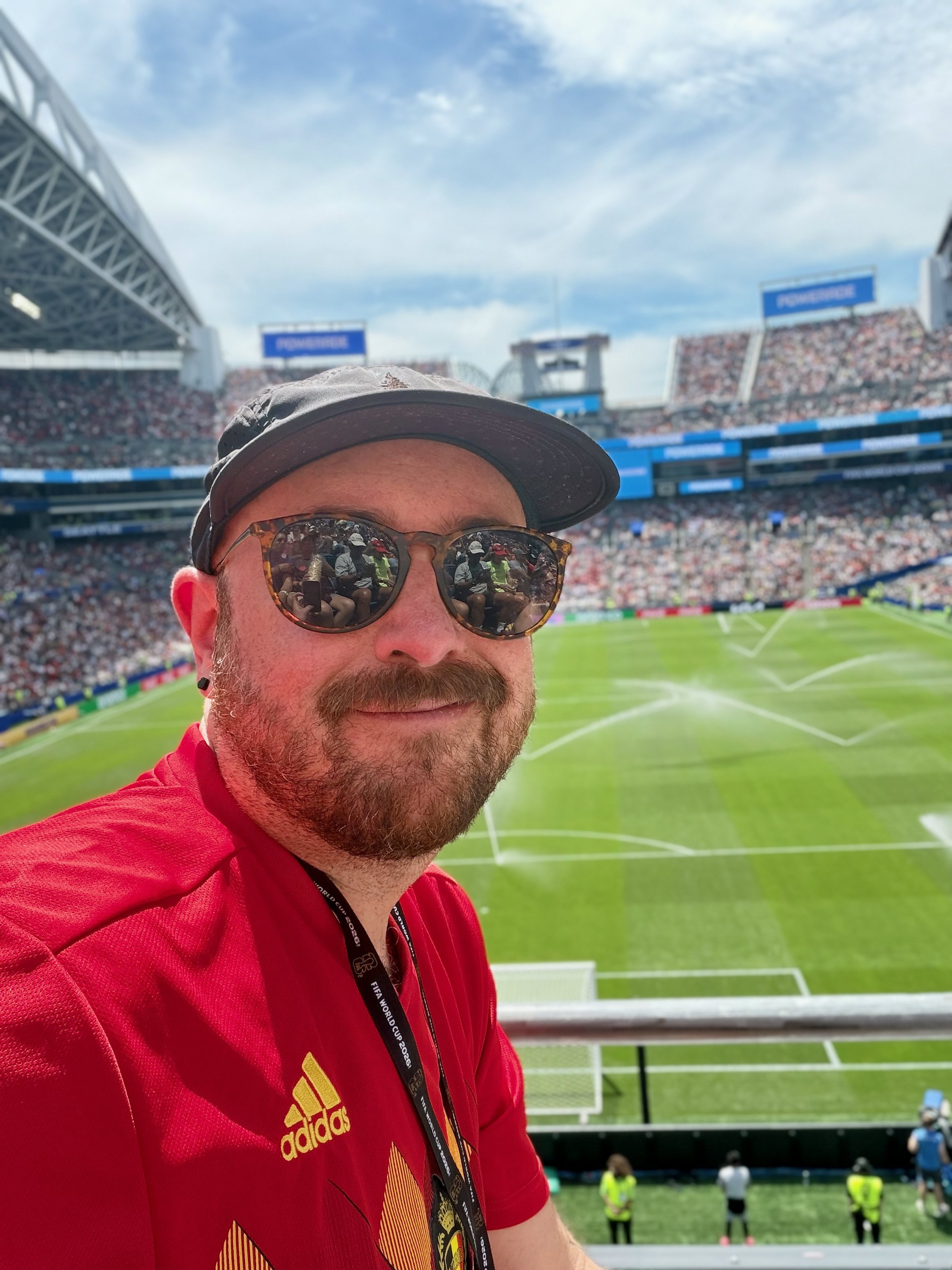 A traveler at a packed world cup match soccer stadium with the field behind him.