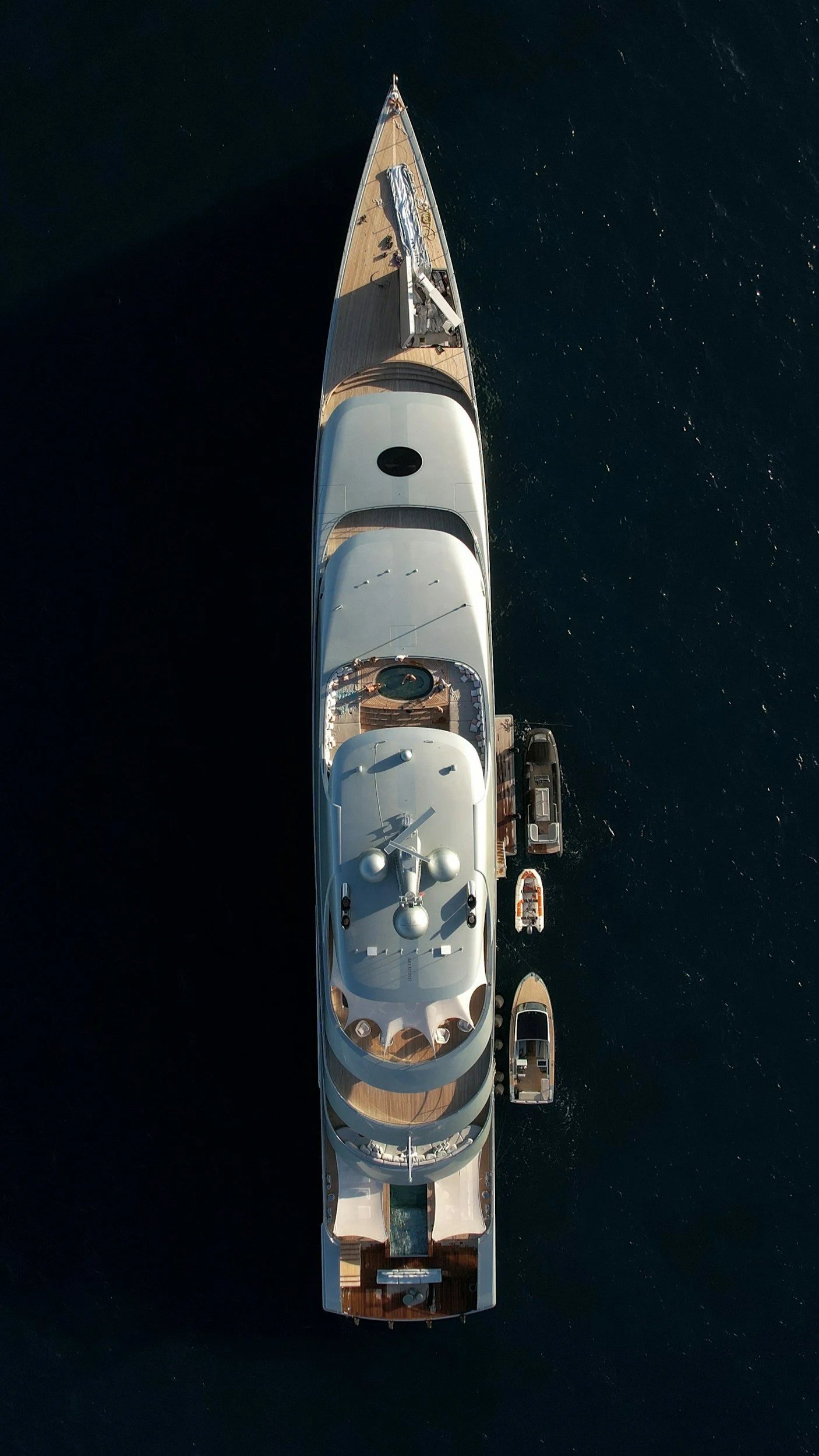 A small luxury yacht viewed from directly above on dark blue water.