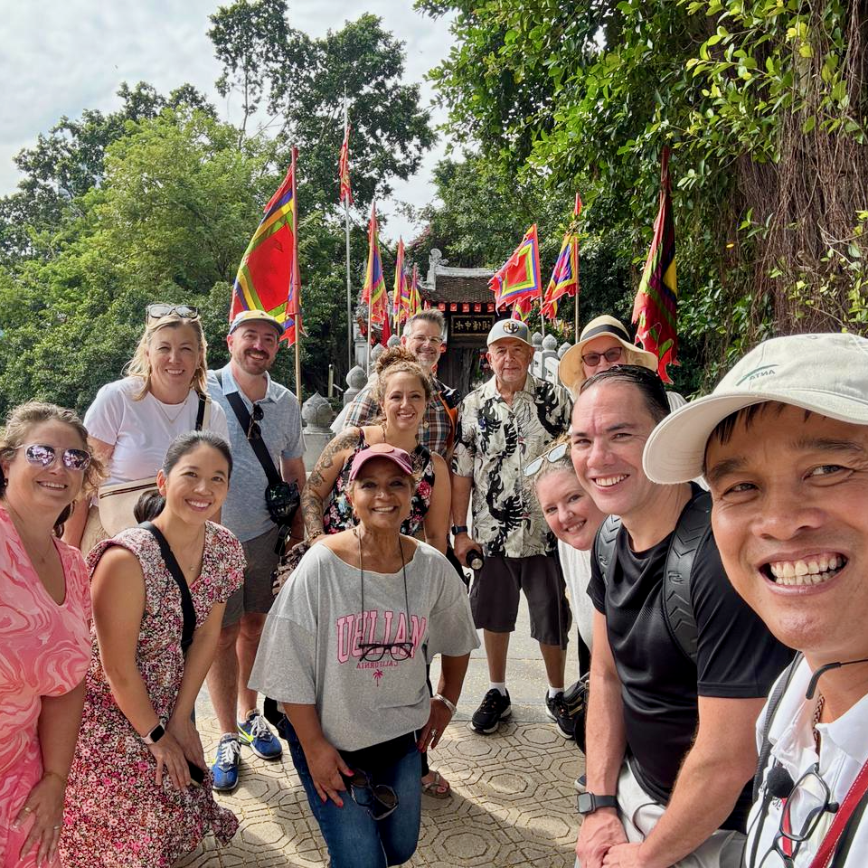 A group of travelers smiling together outdoors in Hanoi during a group trip.