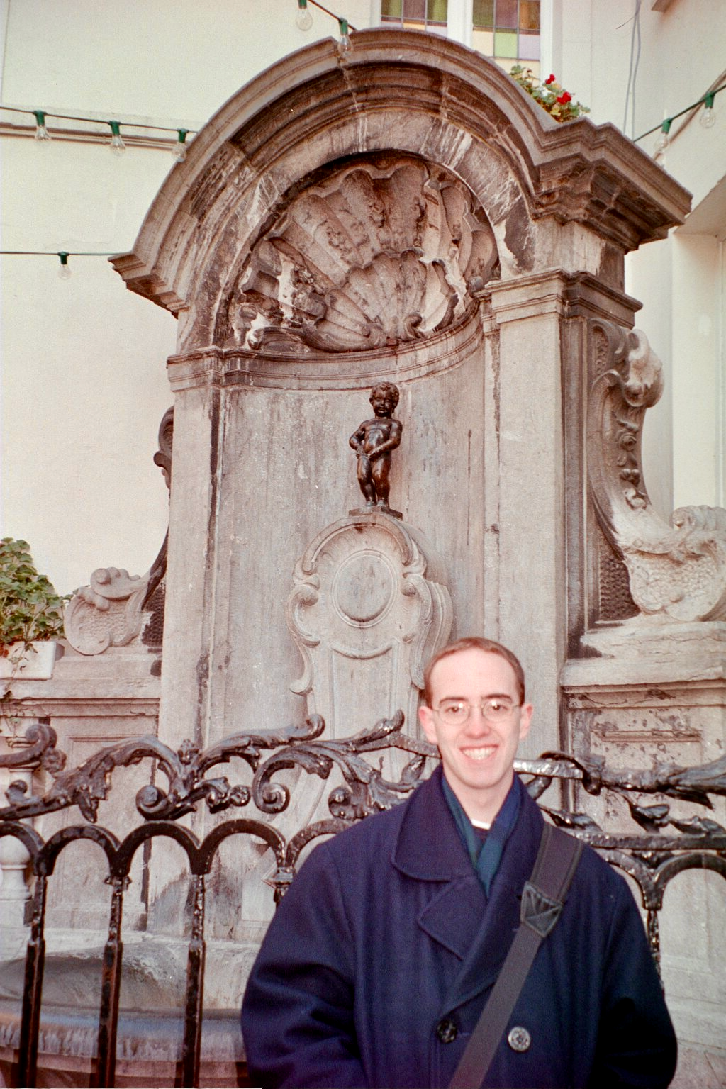 A young traveler standing beside the Manneken Pis fountain in Brussels.