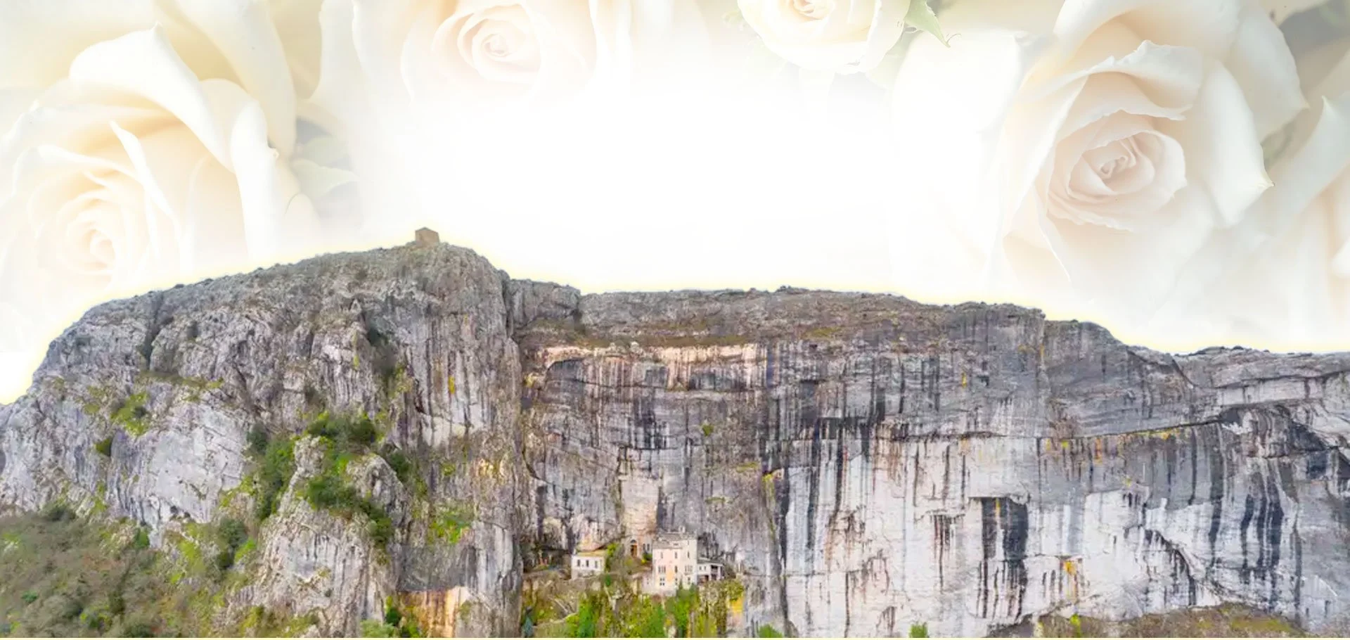 Cliffs with small houses at the base, framed by a border of white roses at the top.