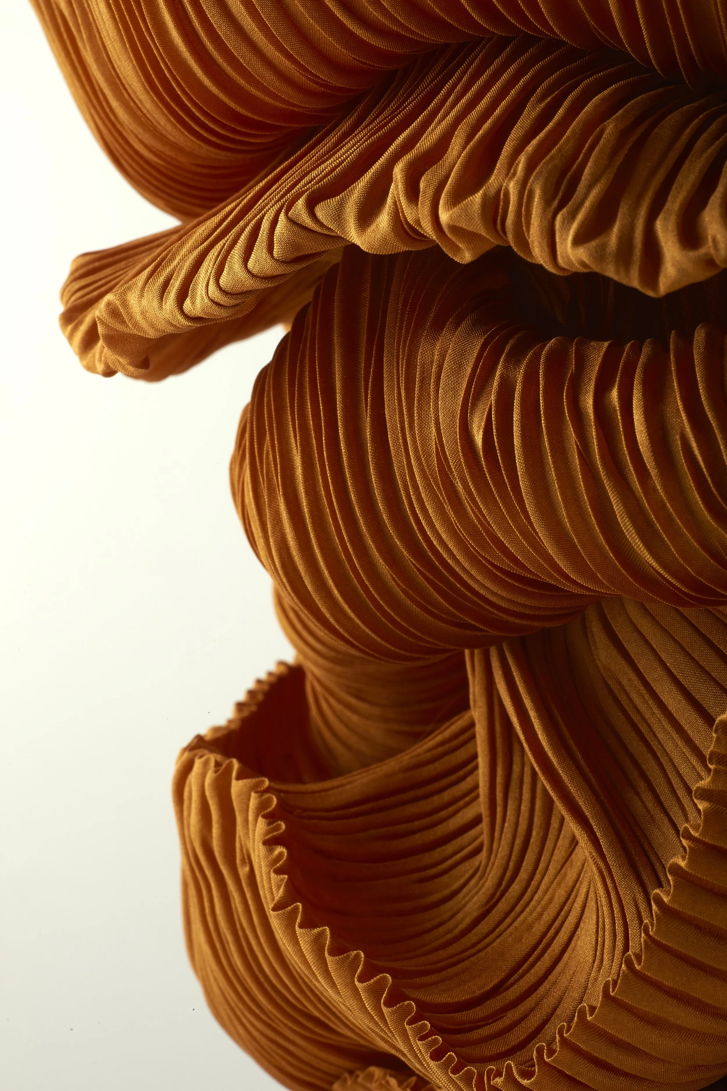 Close-up view of ruffled, pleated, orange fabric with intricate folds and texture.