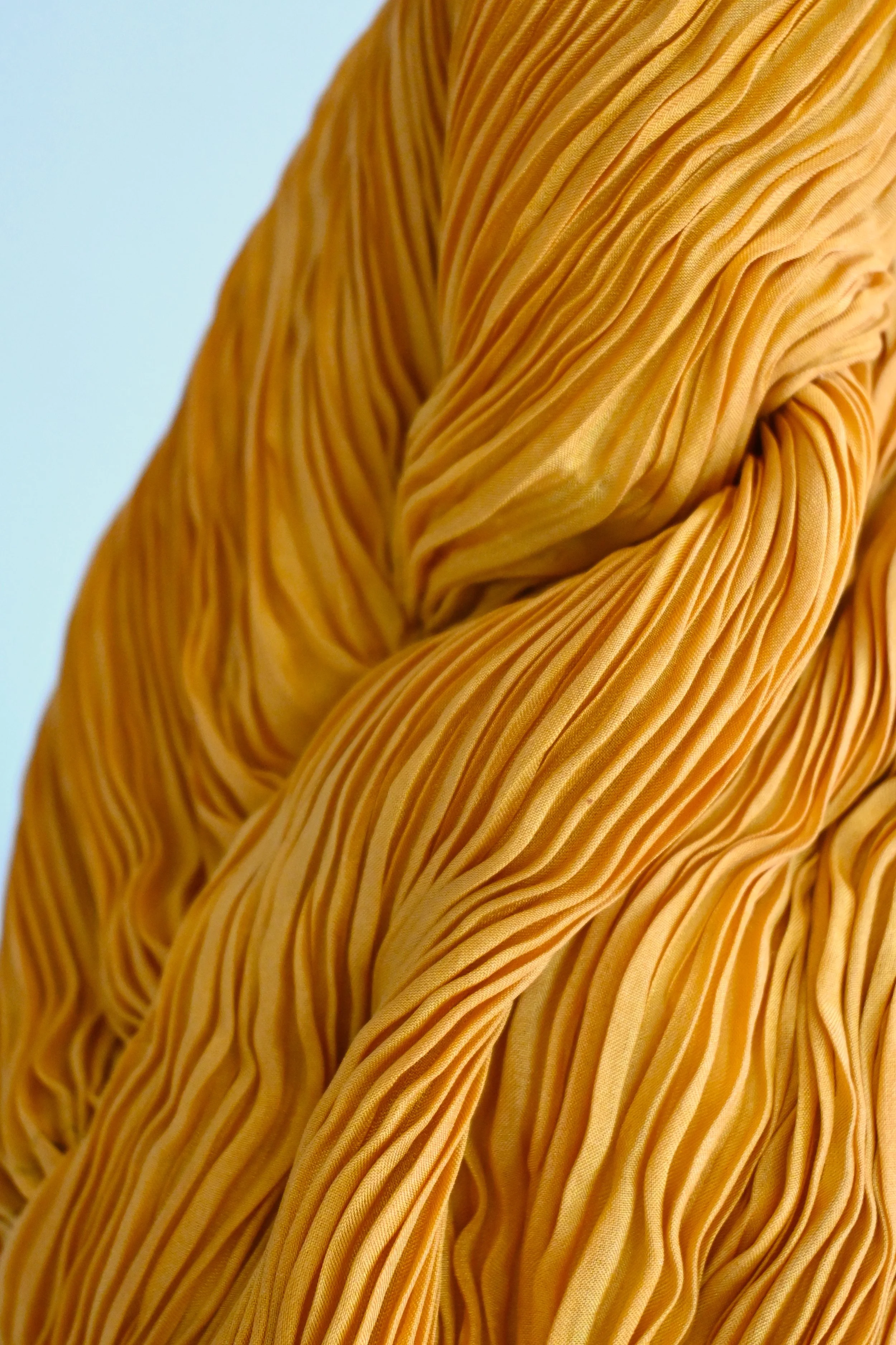 Close-up of a person's torso wearing a yellow pleated blouse with textured vertical stripes.