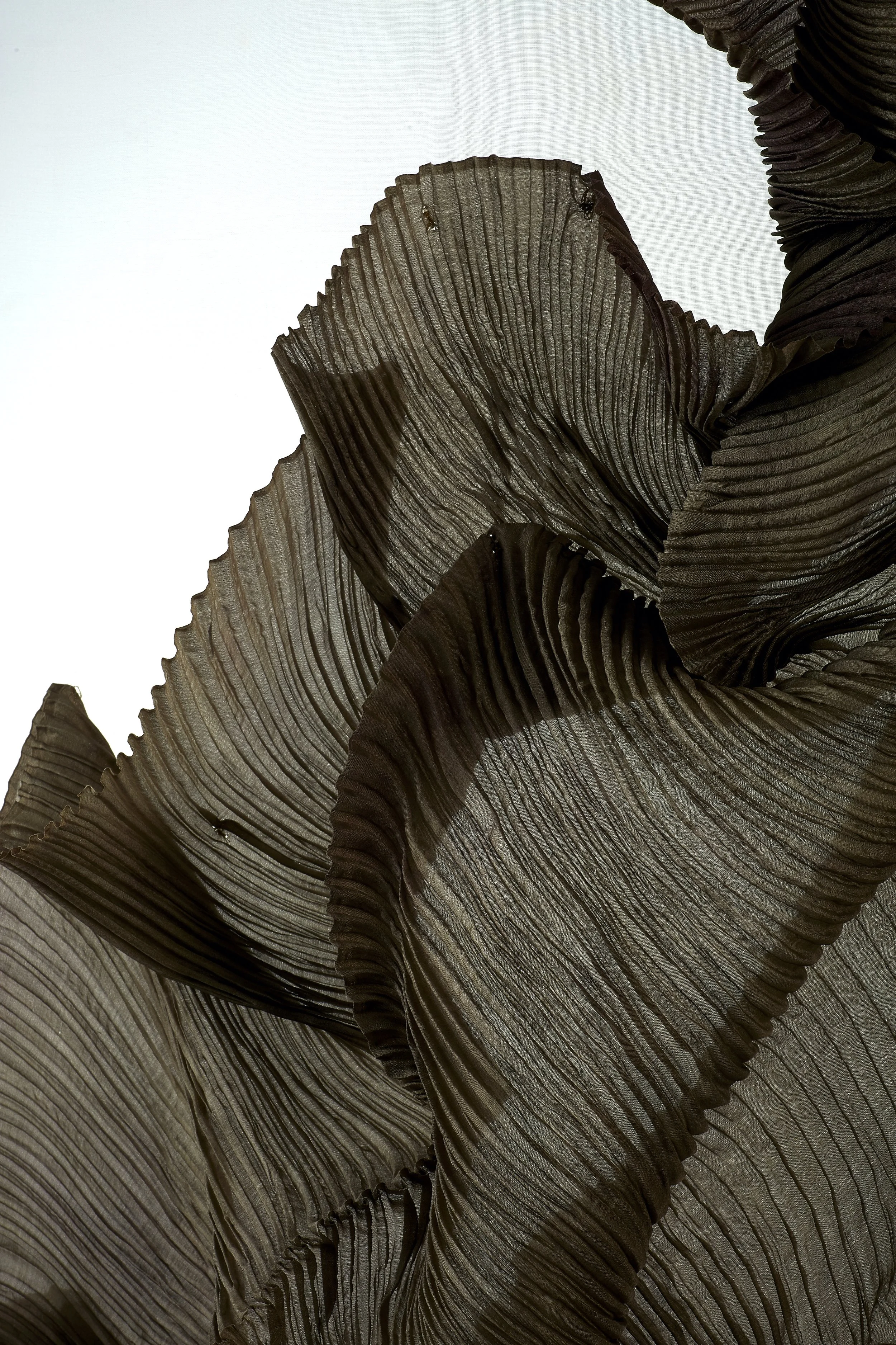 Close-up of dark, textured, pleated fabric with wavy lines and folds.