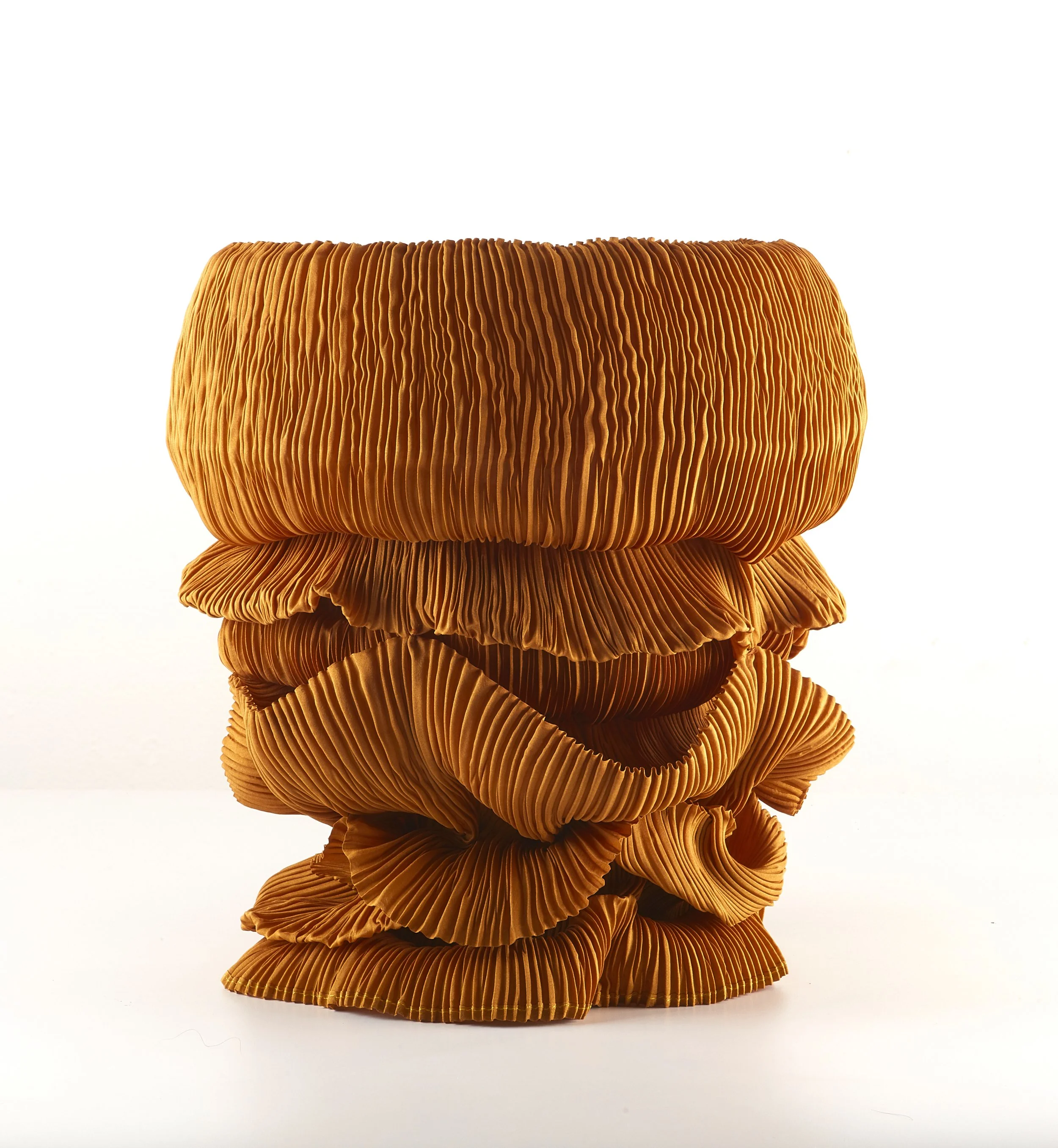 A close-up of a stack of orange, pleated, circular fabric pieces with a ruffled edge, set against a plain white background.