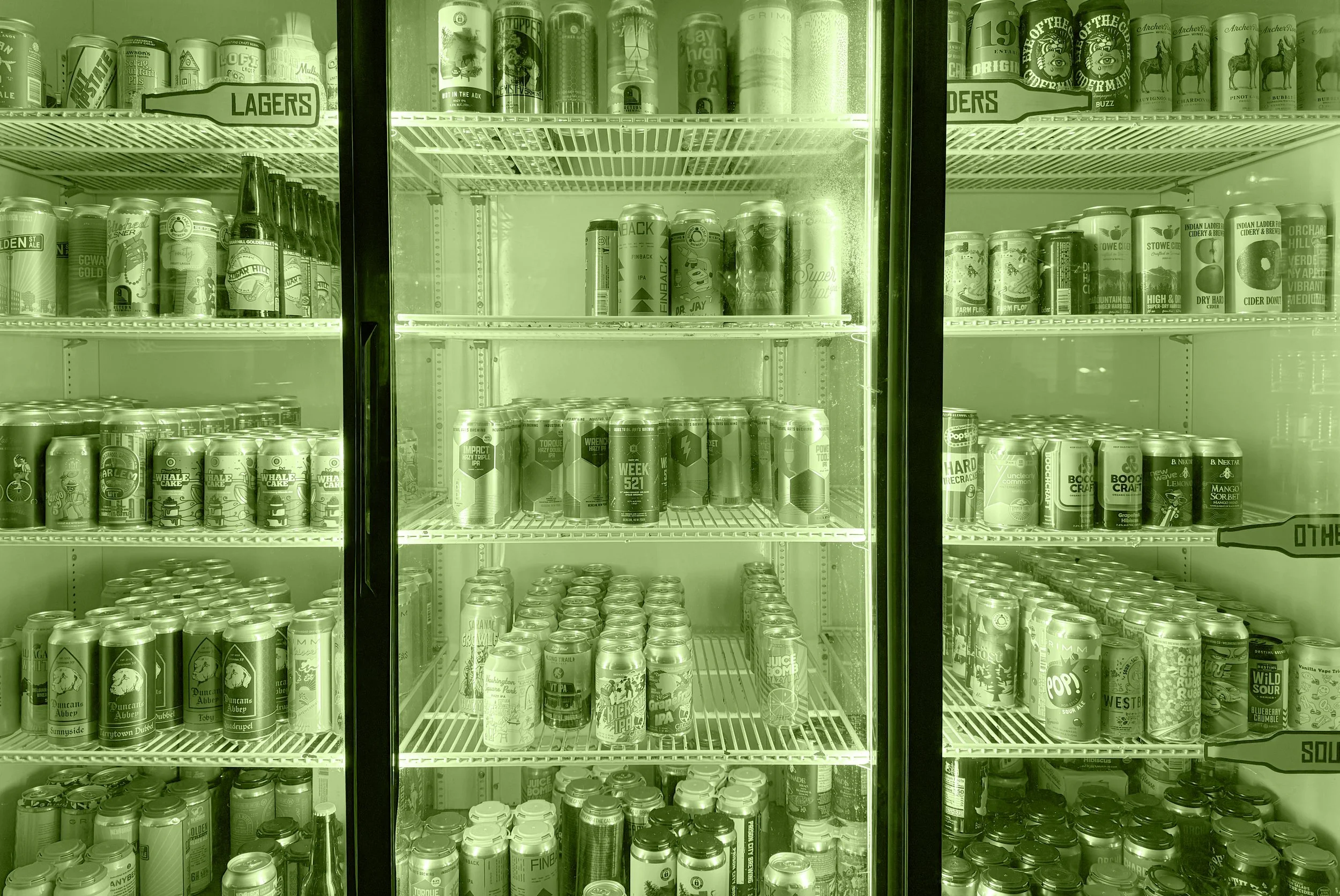 A refrigerated display case filled with various cans and bottles of beer and cider, with a sign labeled 'Lagers' inside.