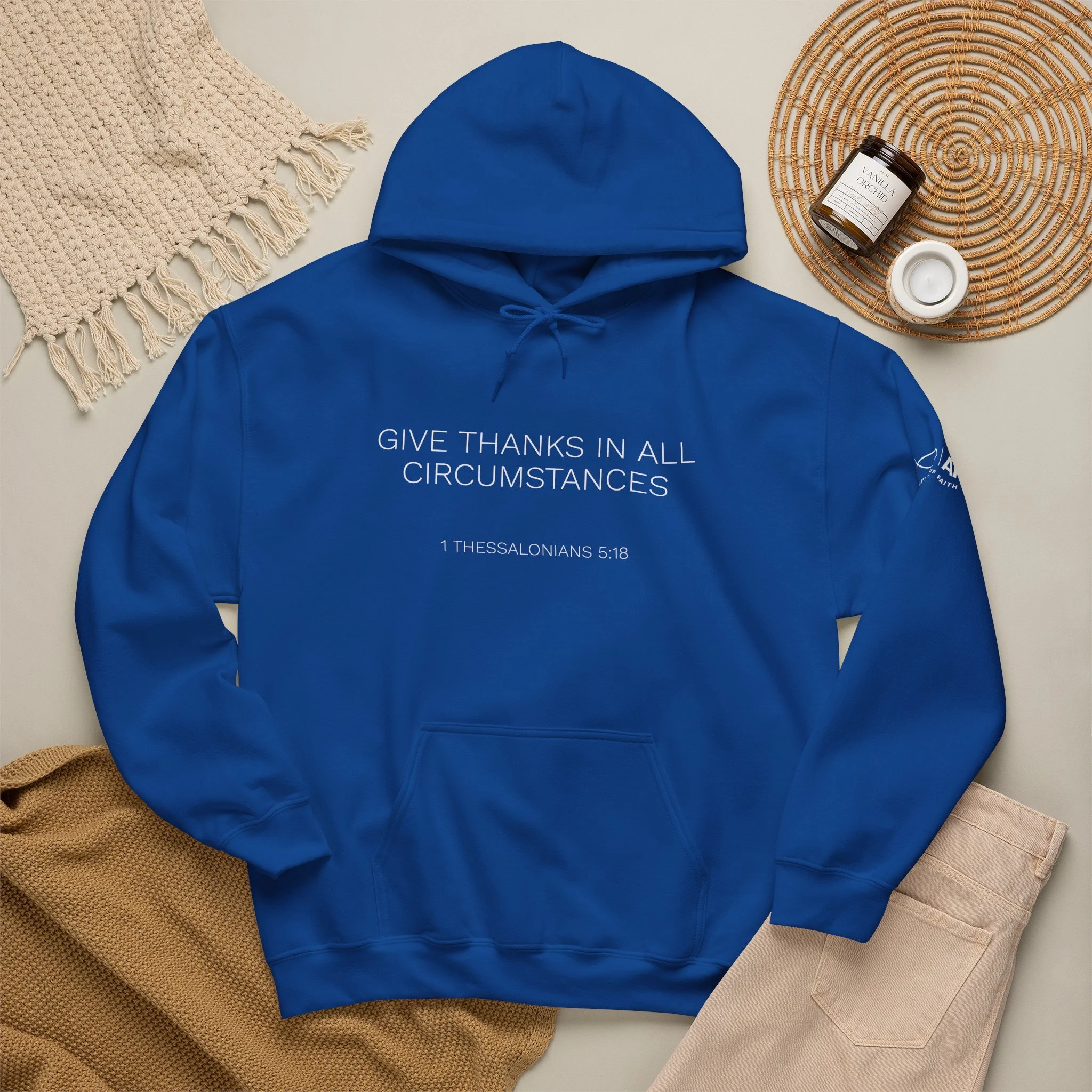 A blue hoodie with religious text and a Bible verse printed on it, Lifestyle flat lay featuring Articles of Faith Scripture-inspired apparel with GIVE THANKS on the front.