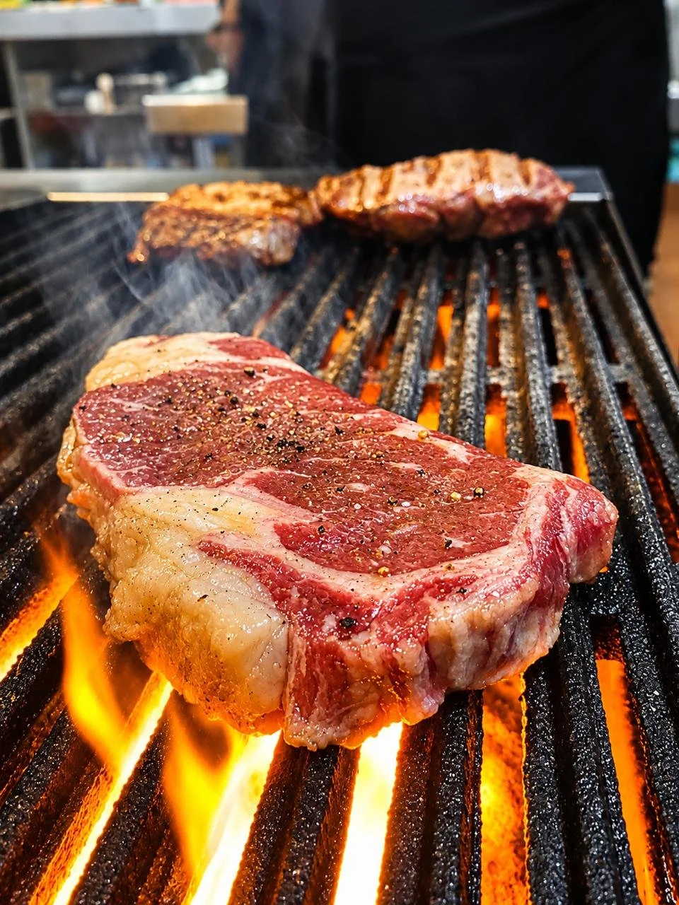 Carne a la parrilla cocinándose sobre una parrilla con fuego y llamas