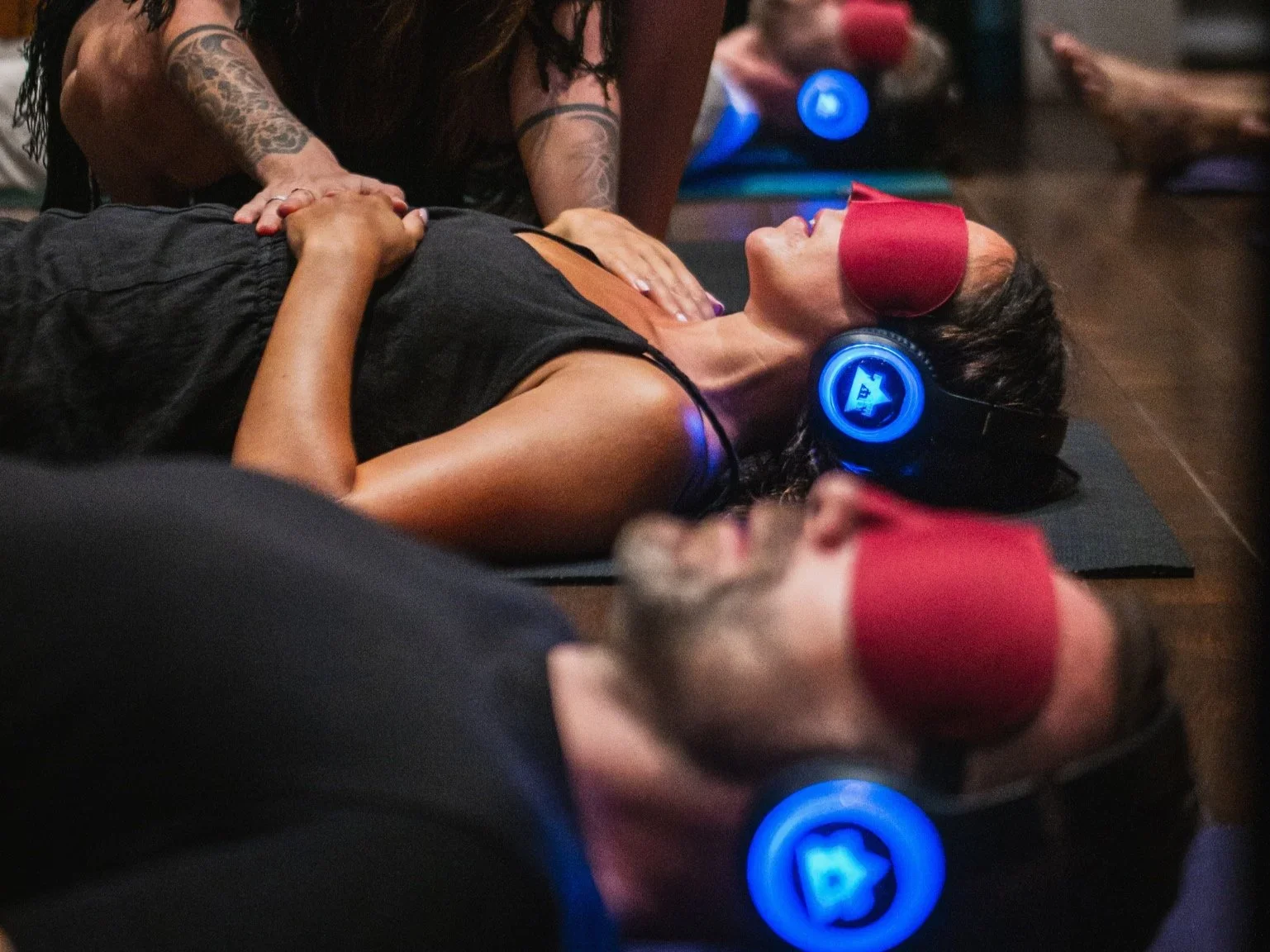 Women lying on yoga mats during a sound healing session with headphones and eye masks.