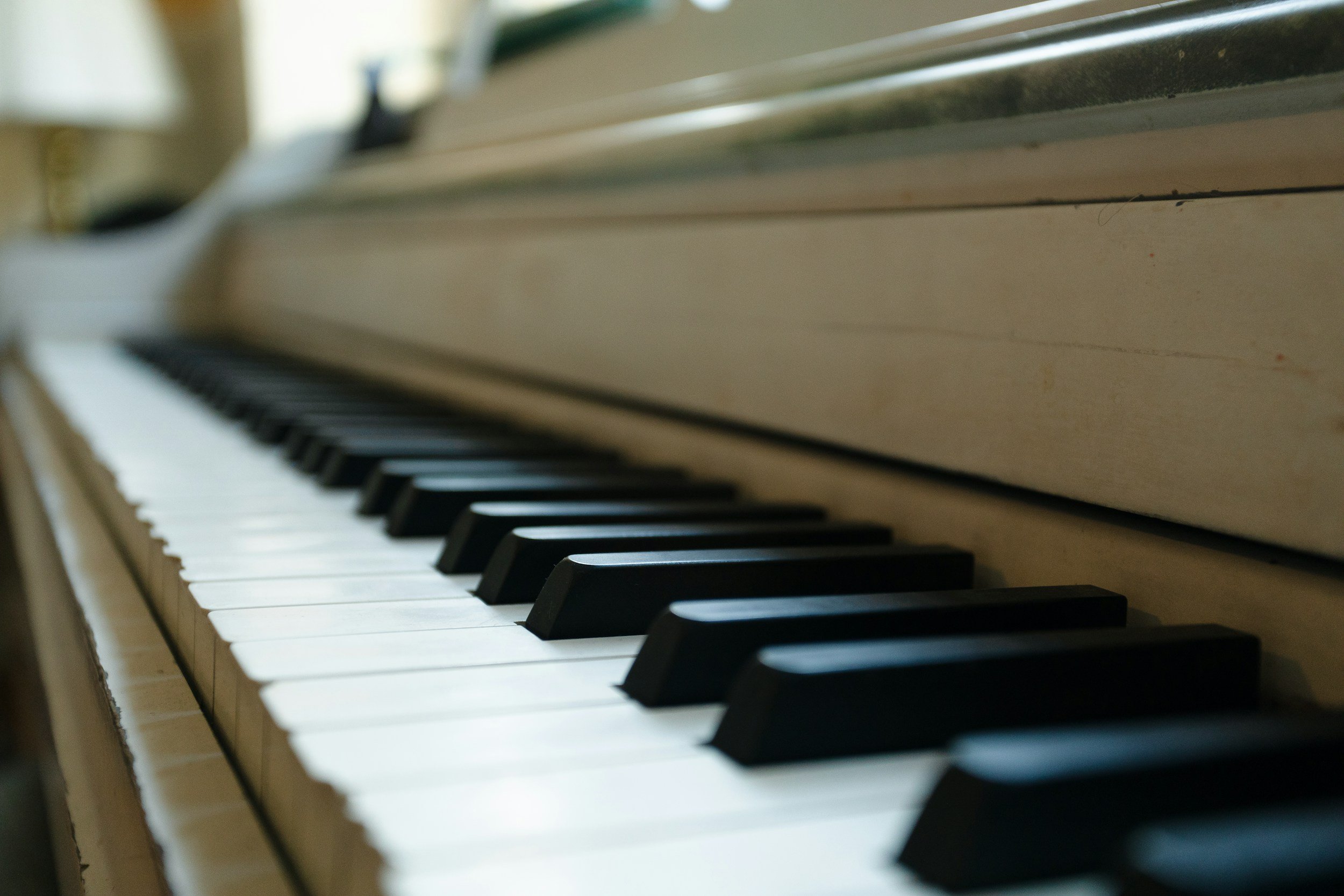 Close-up of black and white piano keys, focusing on the white keys with the black keys blurred in the background.