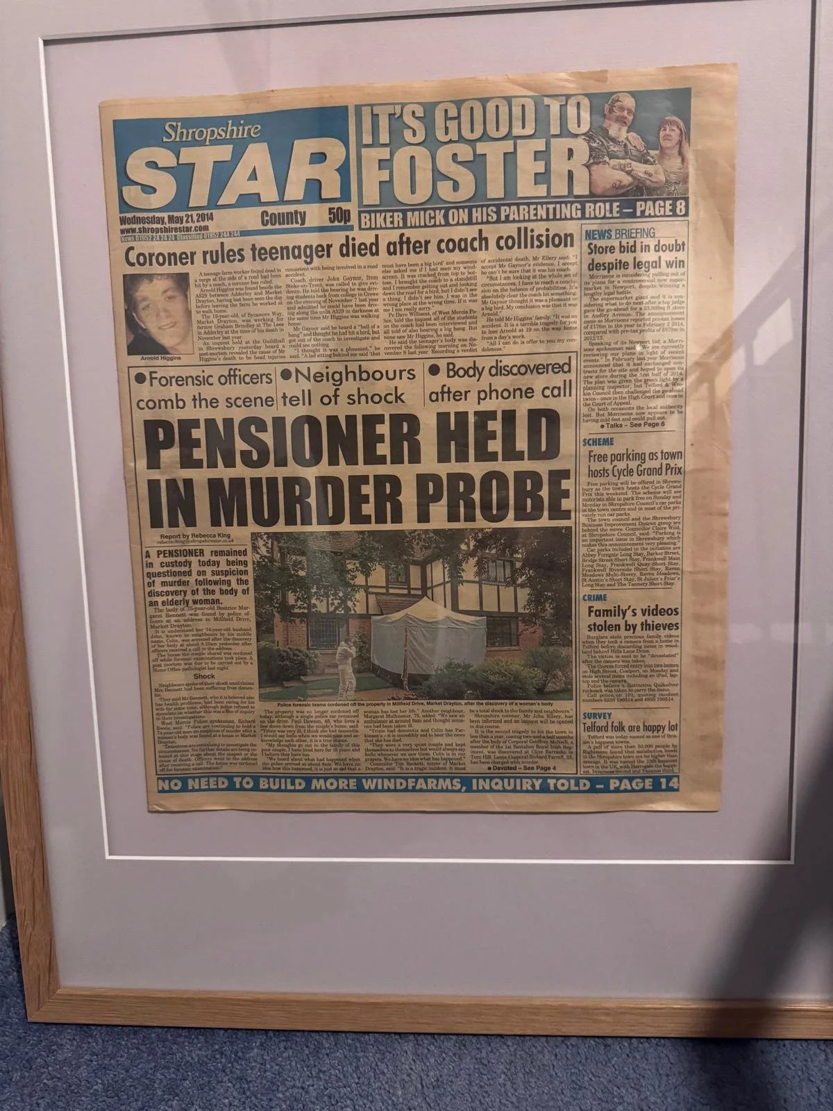 Framed newspaper page with headlines about a death, a murder investigation, and other local news.