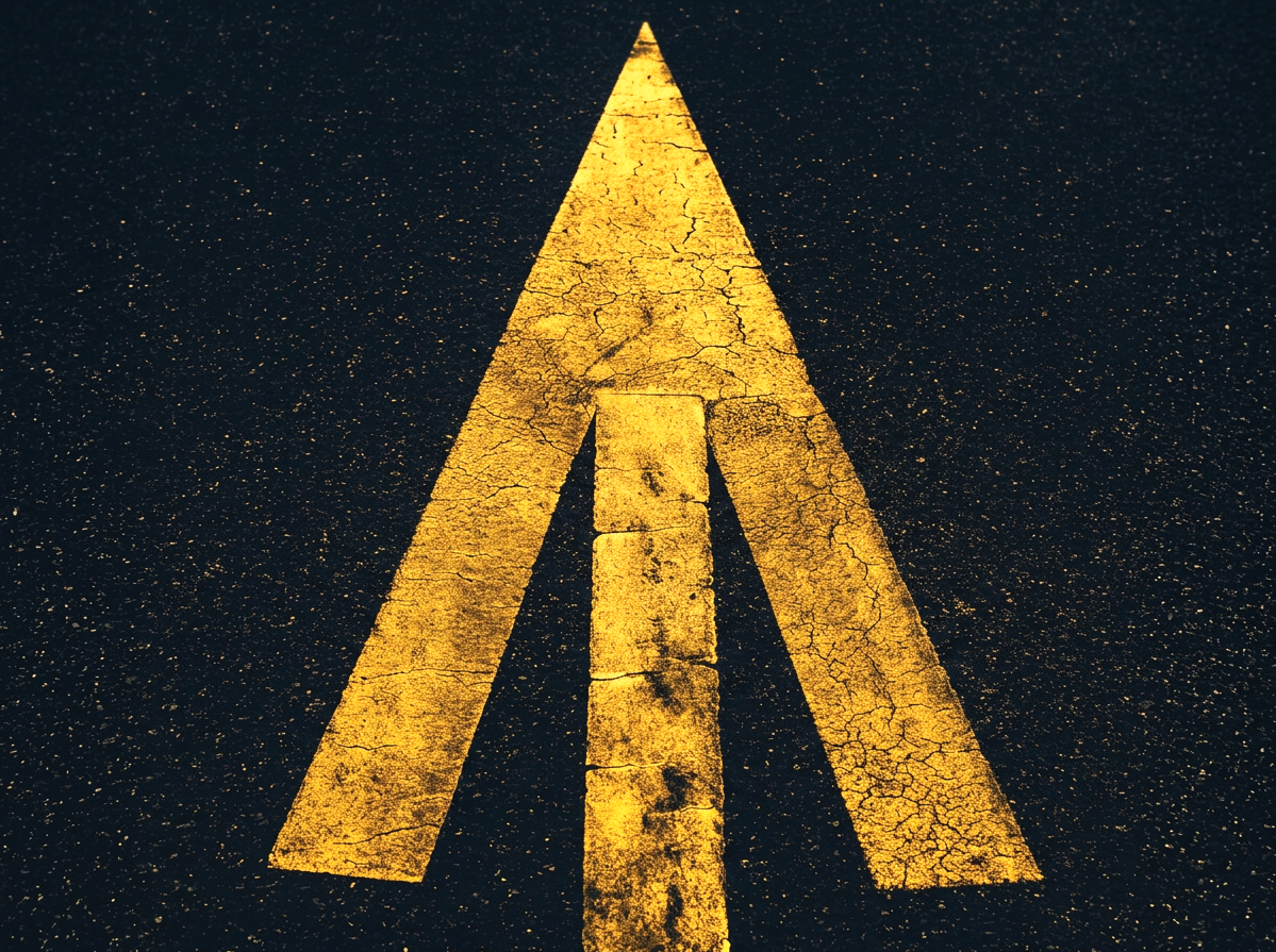Image of a large yellow driving lane arrow on asphalt.