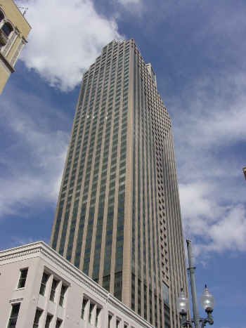 Tall skyscraper with a modern glass and concrete exterior against a partly cloudy sky.