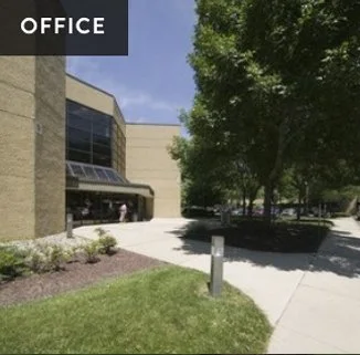 Exterior view of an office building with trees and a sidewalk