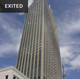A tall skyscraper with a modern glass facade against a partly cloudy sky.