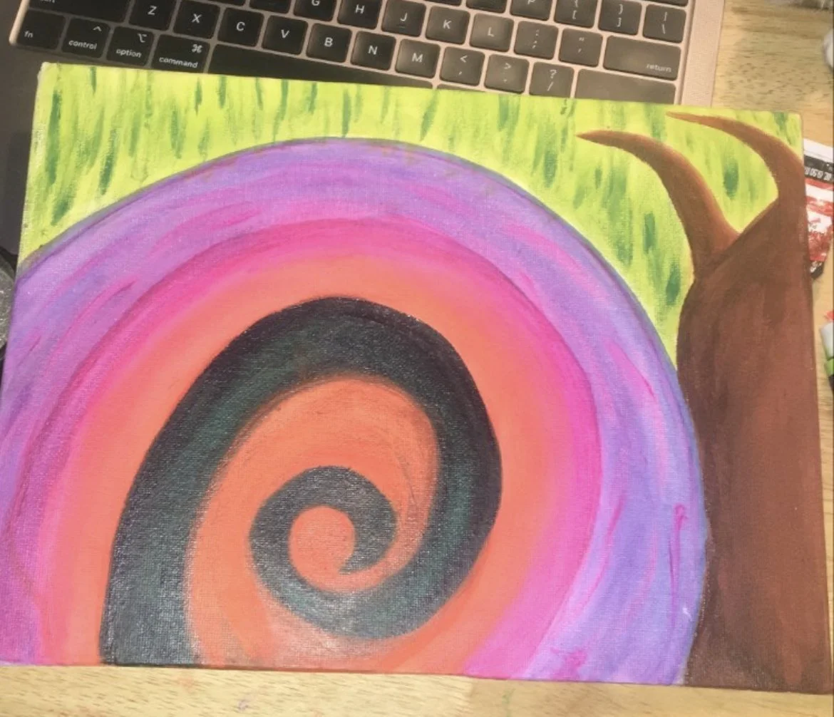 A colorful drawing of a snail with a spiral shell, featuring shades of orange, pink, purple, and black, and a brown body with two curved antennae. The background is green, representing grass or foliage.
