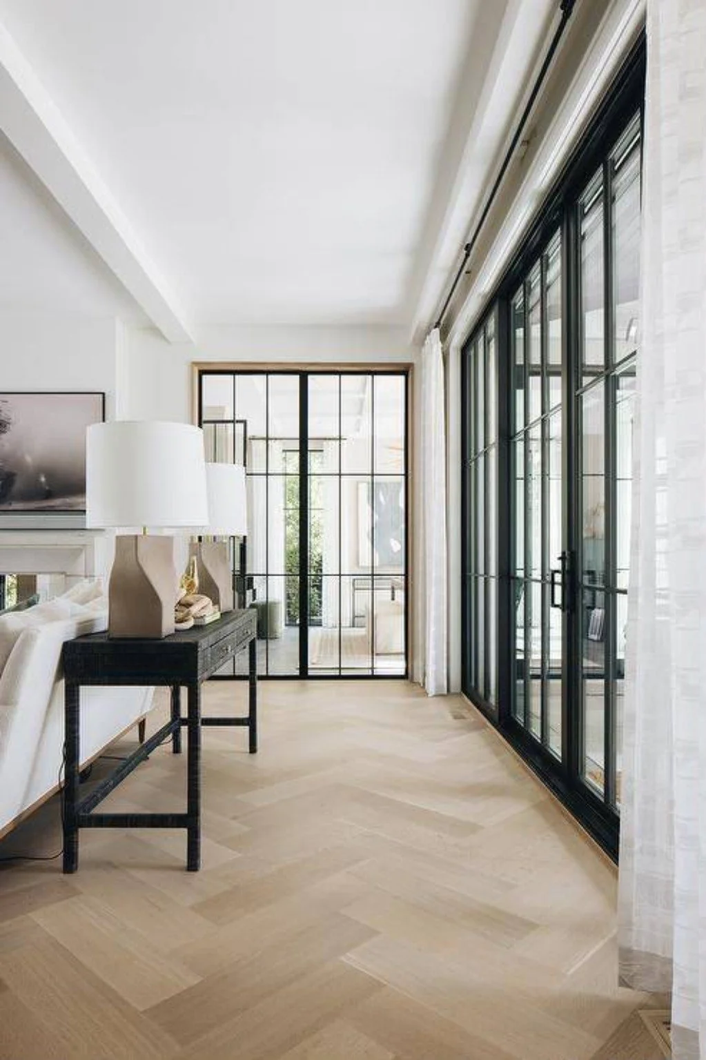 Light wood-look herringbone flooring with black-framed glass doors.