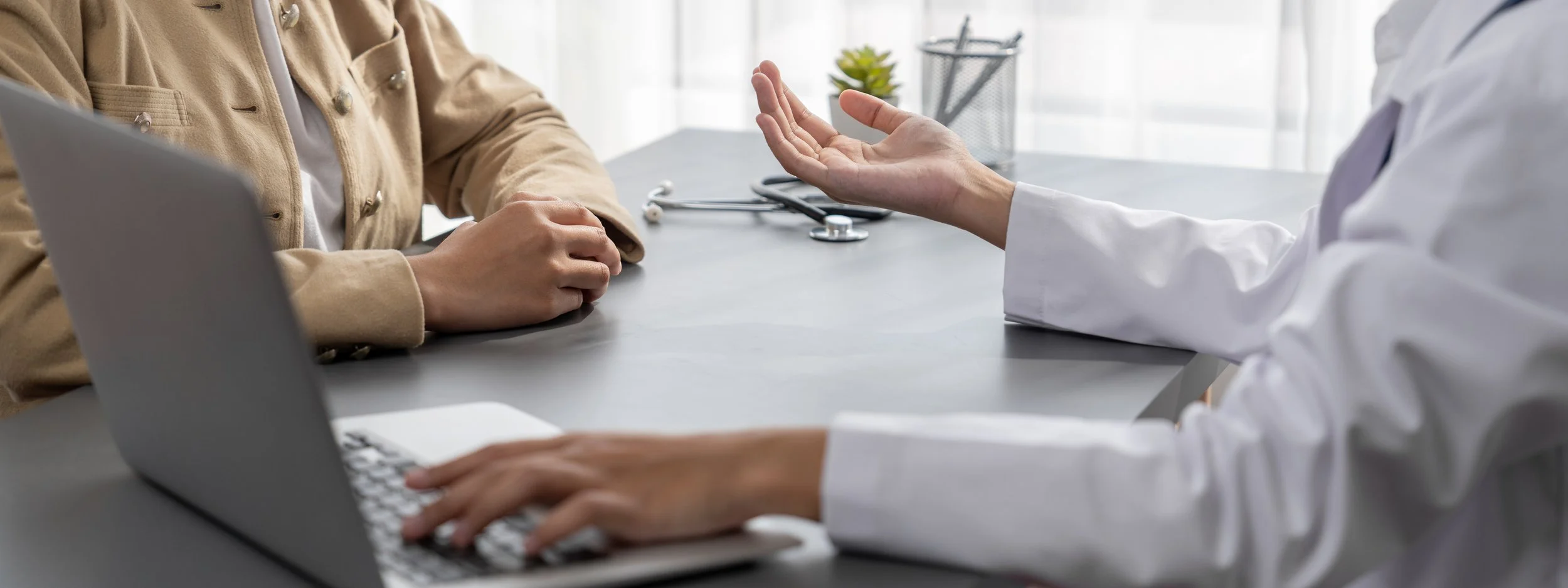 Patient and clinician talking across a desk during a psychiatric evaluation