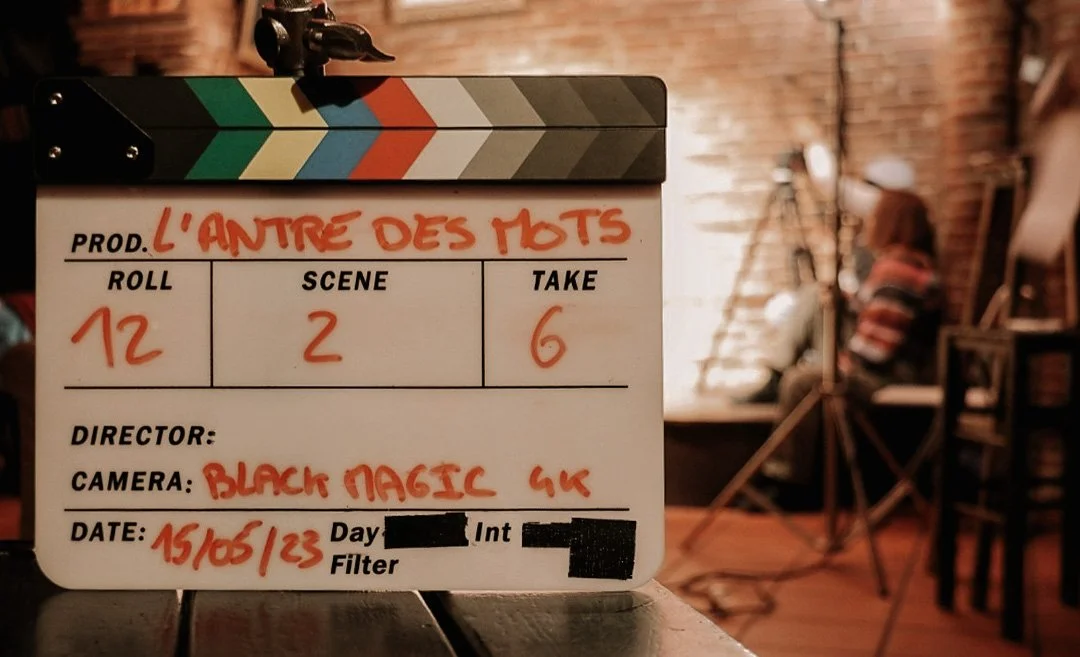 Clap de tournage cinéma sur un plateau de film avec éclairage chaud et décor en briques.