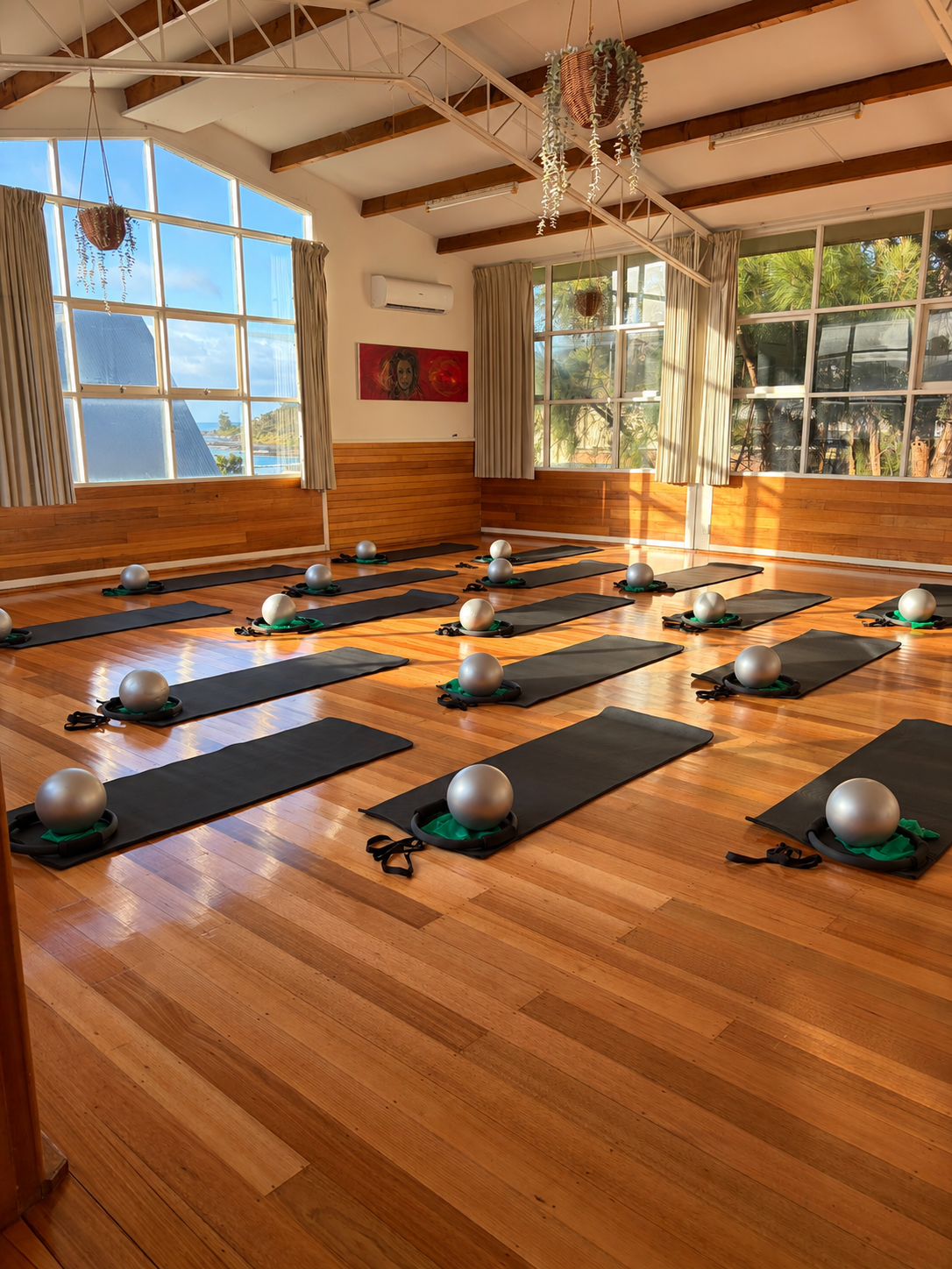 Bright Pilates class space in Lorne, Victoria, with timber floors, large windows, mats and exercise equipment.