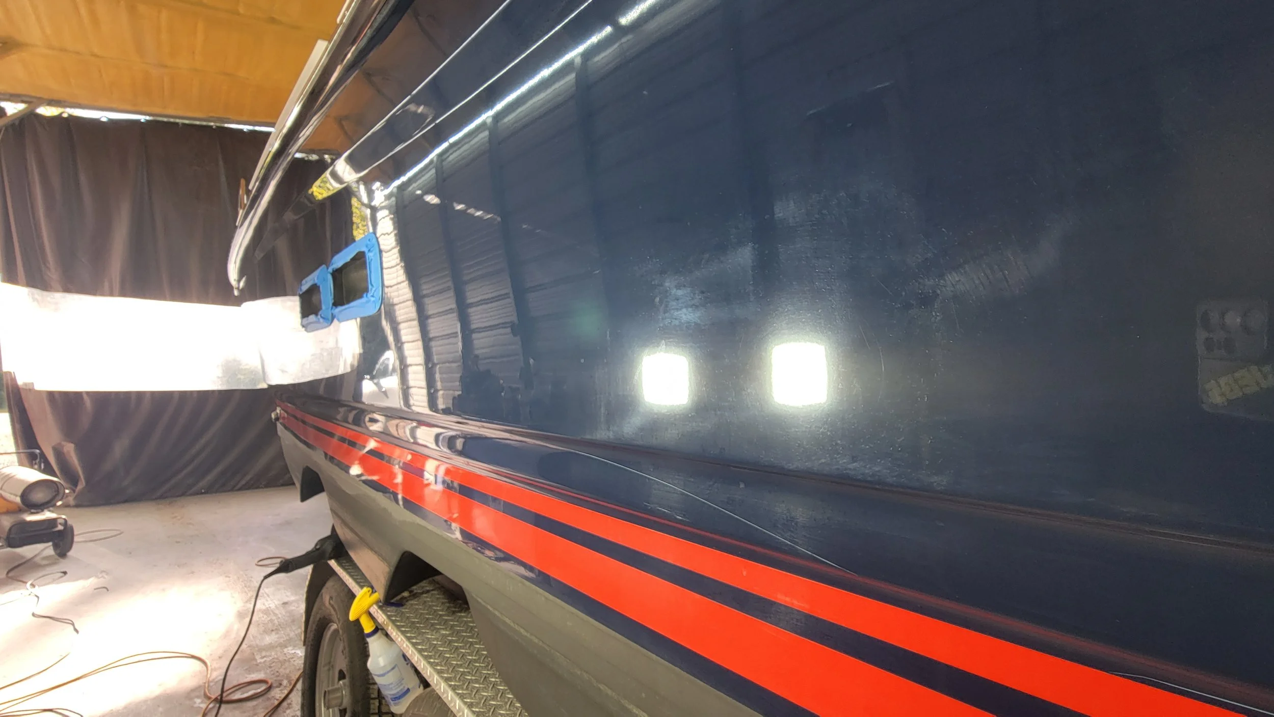 Close-up of a dark blue vehicle with red stripes and reflective trim inside a workshop
