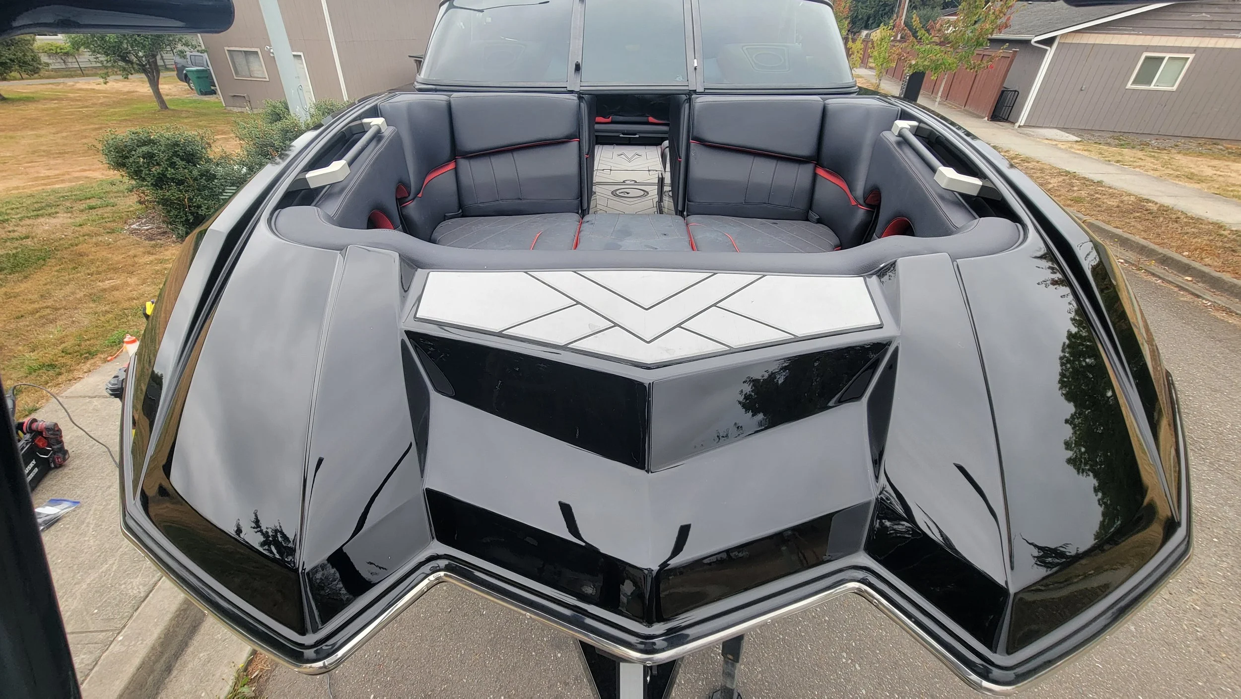 Rear seating and angular engine cover of a black-and-white personal watercraft parked in a residential driveway