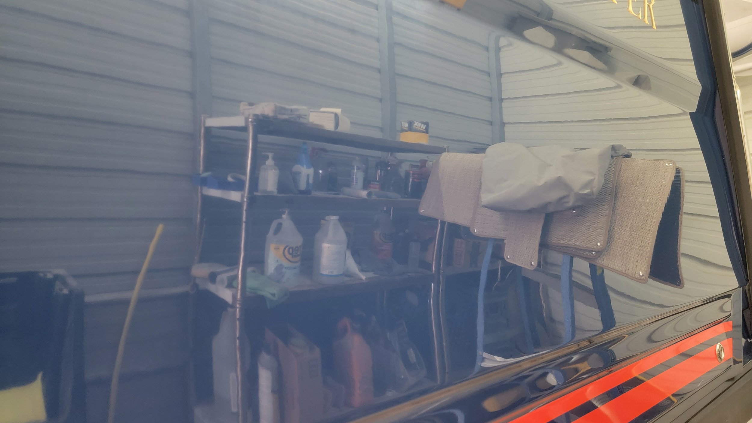 Shelving unit stocked with cleaning supplies beside a folding chair in a garage