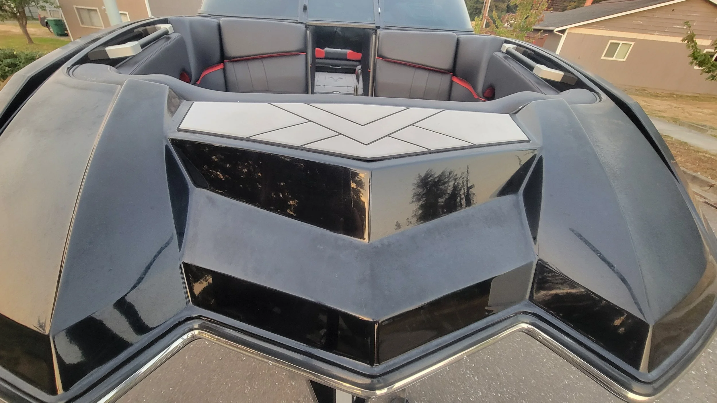 Rear deck and seating area of a black and gray pontoon boat with red-accented seats.