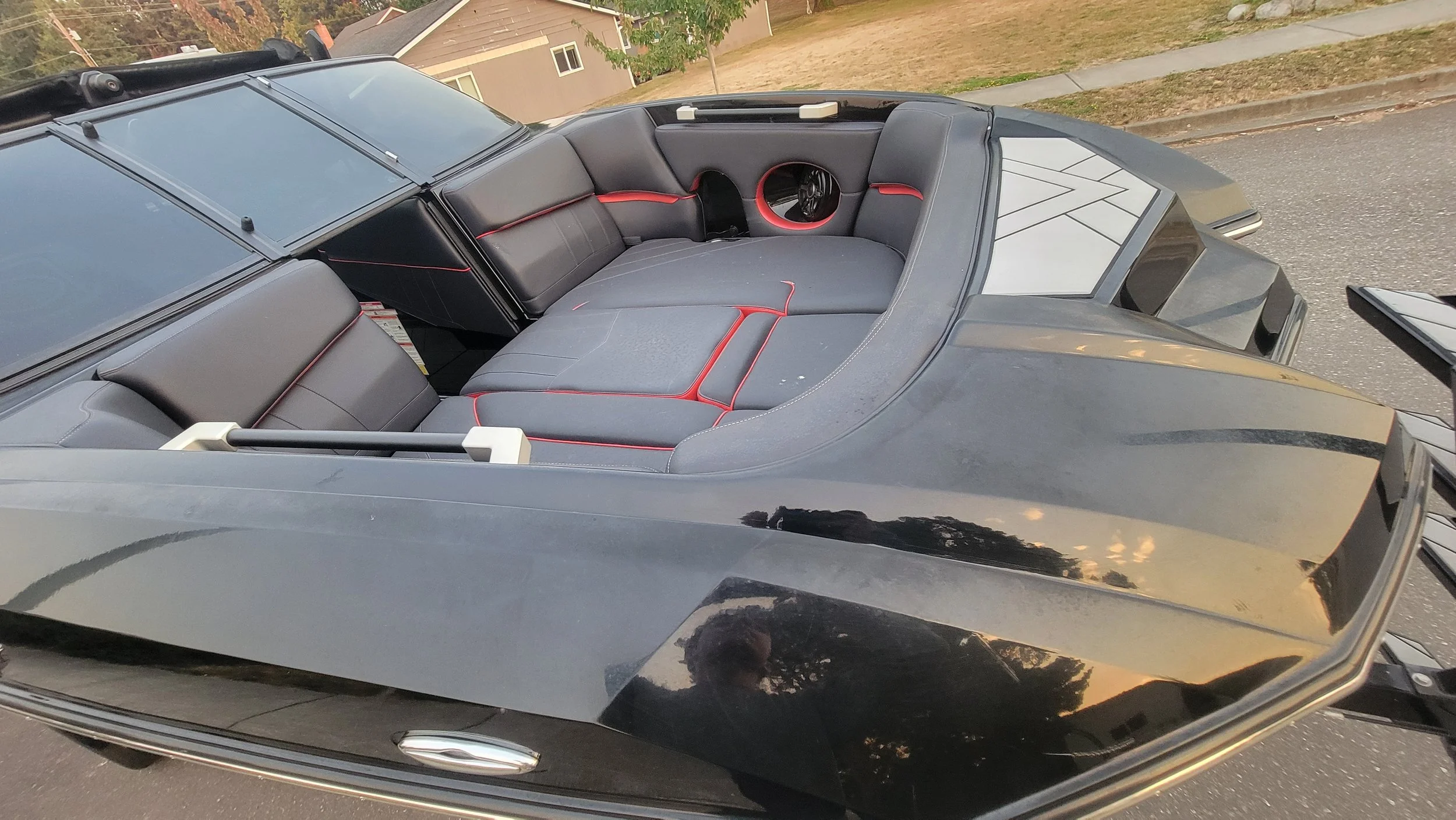 Custom black sports car interior with gray leather seats, red trim, and circular rear speakers