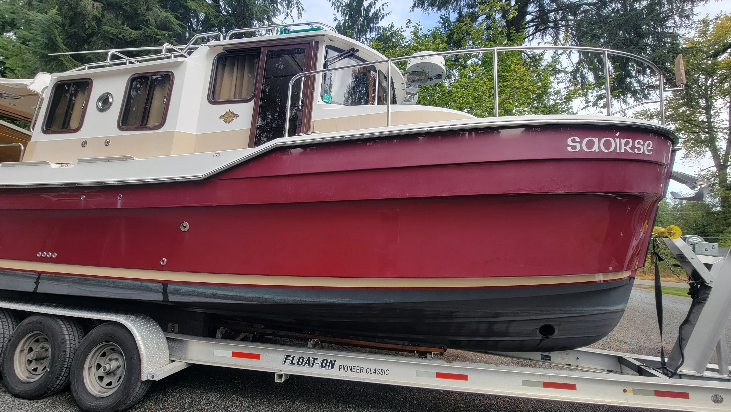 Burgundy and white cabin cruiser named Saoirse on a Float-On trailer outdoors