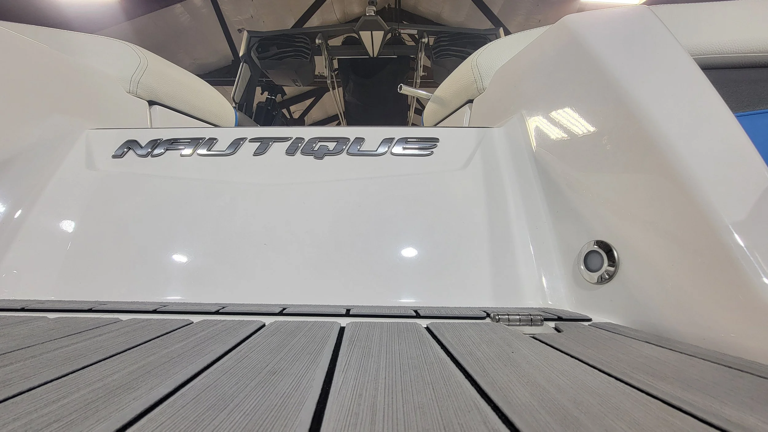 Close-up of a white Neutrino boat stern with exposed twin outboard motors and gray deck flooring