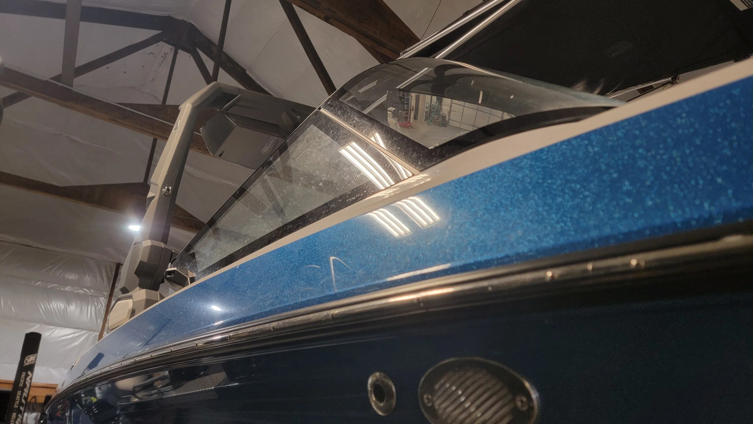 Close-up of a blue vintage car with chrome trim and windshield inside a garage