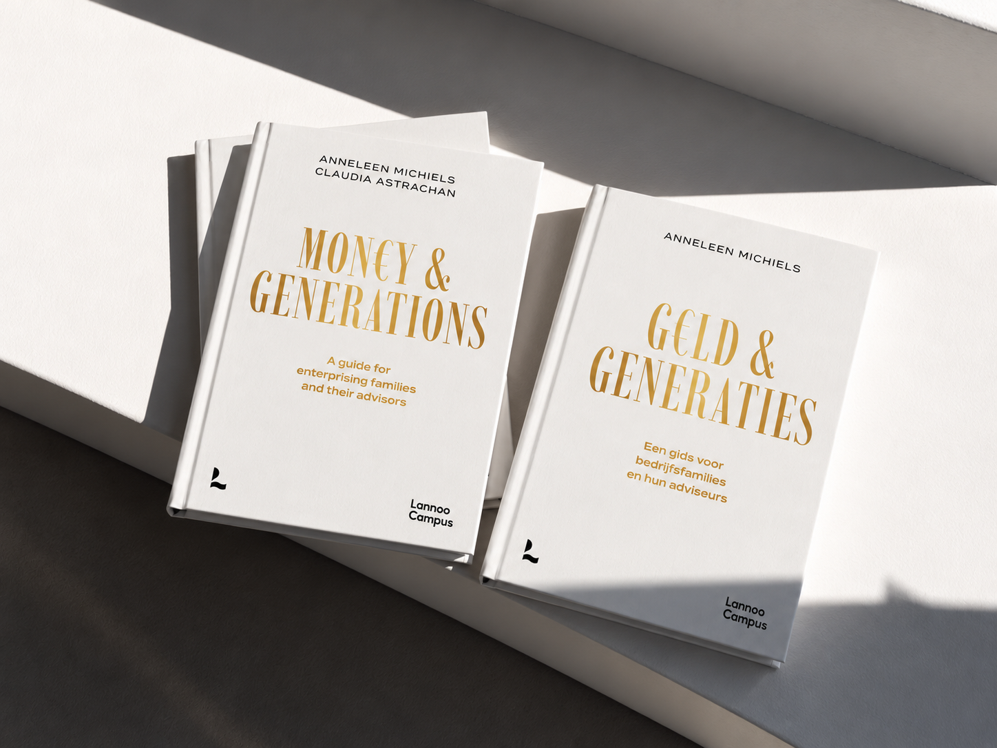 Two white books with gold and black text on the covers, titled 'Money & Generations' and 'Geld & Generaties', by Anneleen Michiels and Claudia Astrachan.