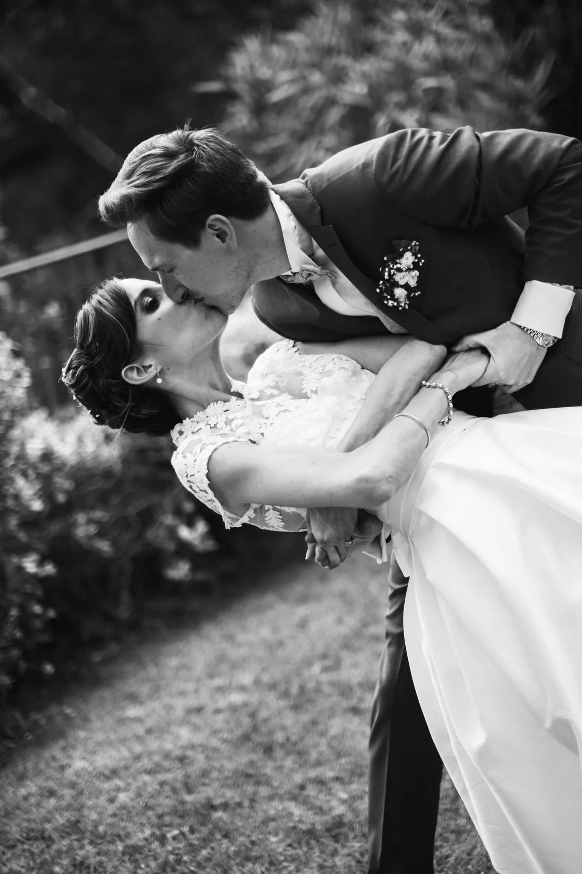 Deux personnes en robe de mariage et costume romantique s'embrassent lors d'un mariage en extérieur.