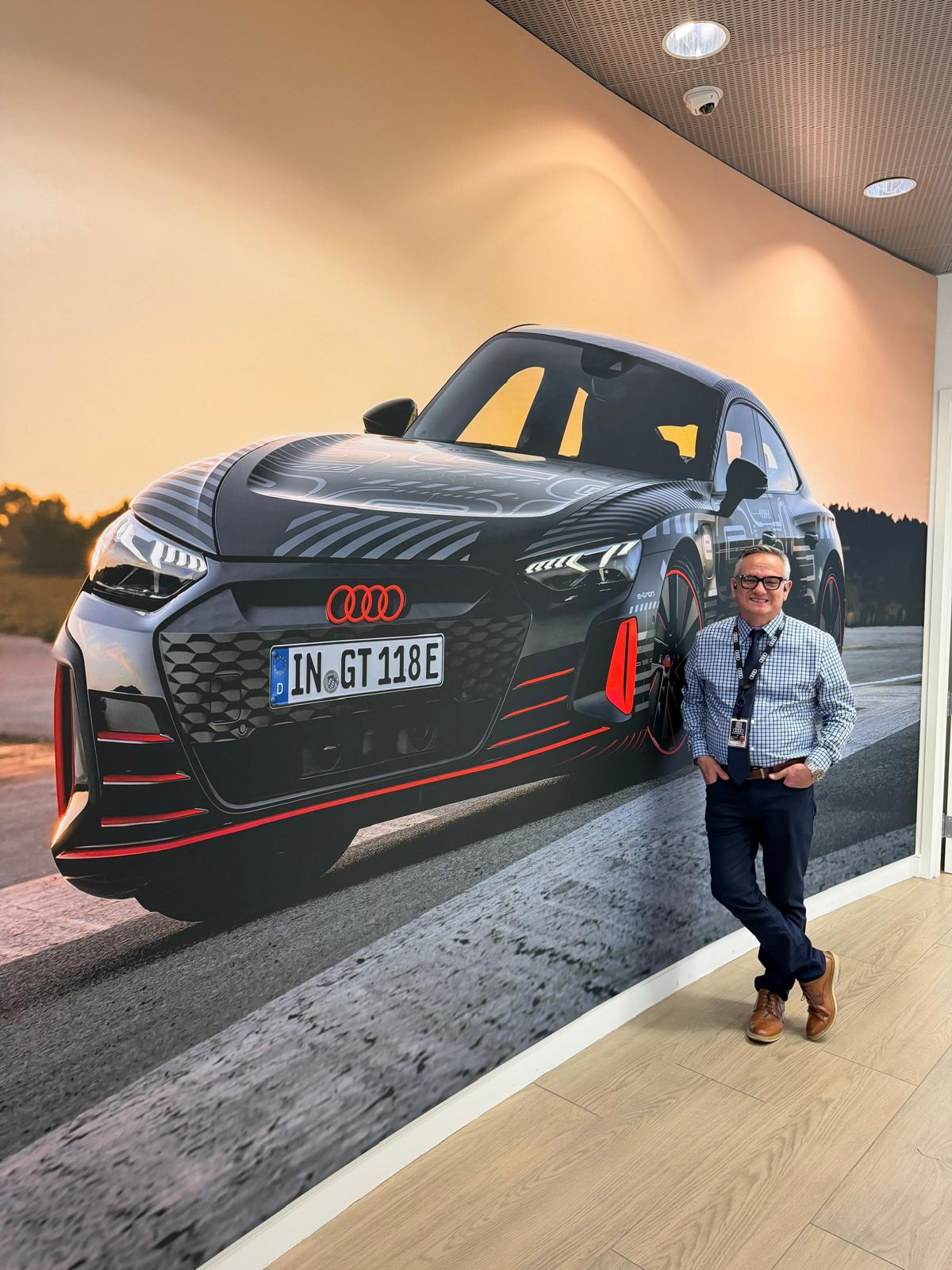 Hernan “H” Diaz-Egg smiling beside an Audi display at Autohaus Lancaster