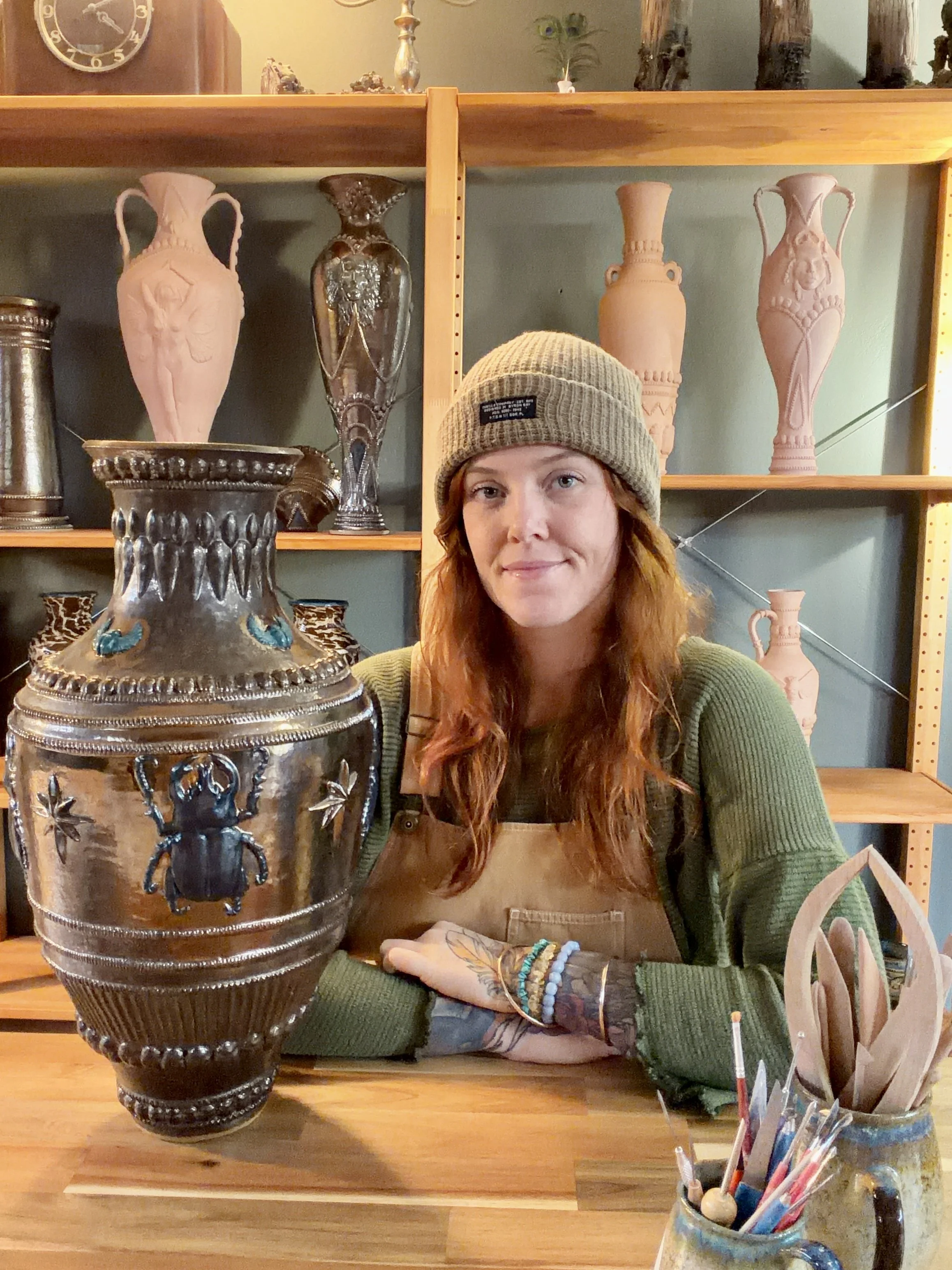 Casey Anne St John in her studio sitting next to her sculptural ceramic vessel called 'What Endures'
