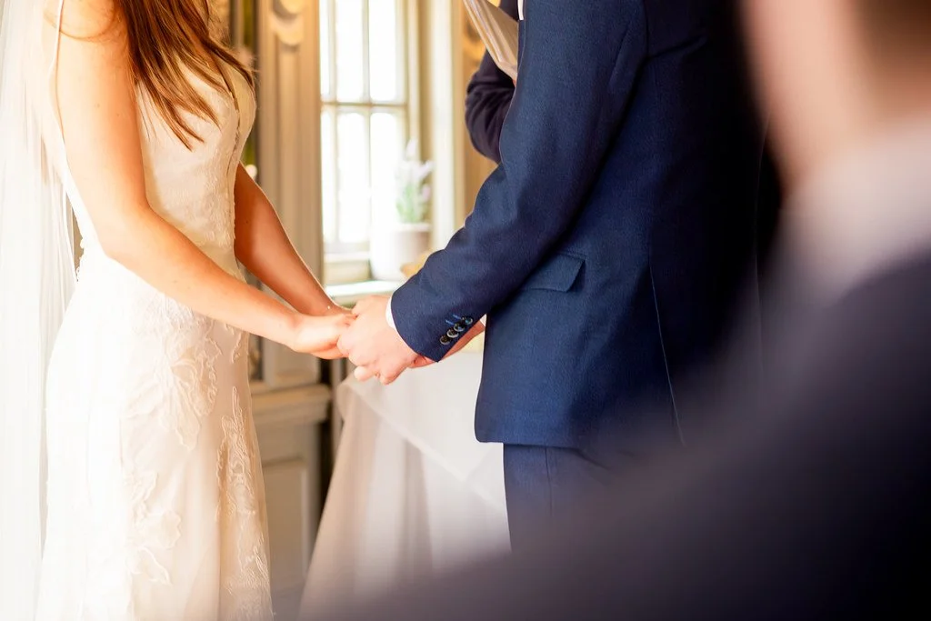 A bride and groom holding hands during their wedding ceremony.