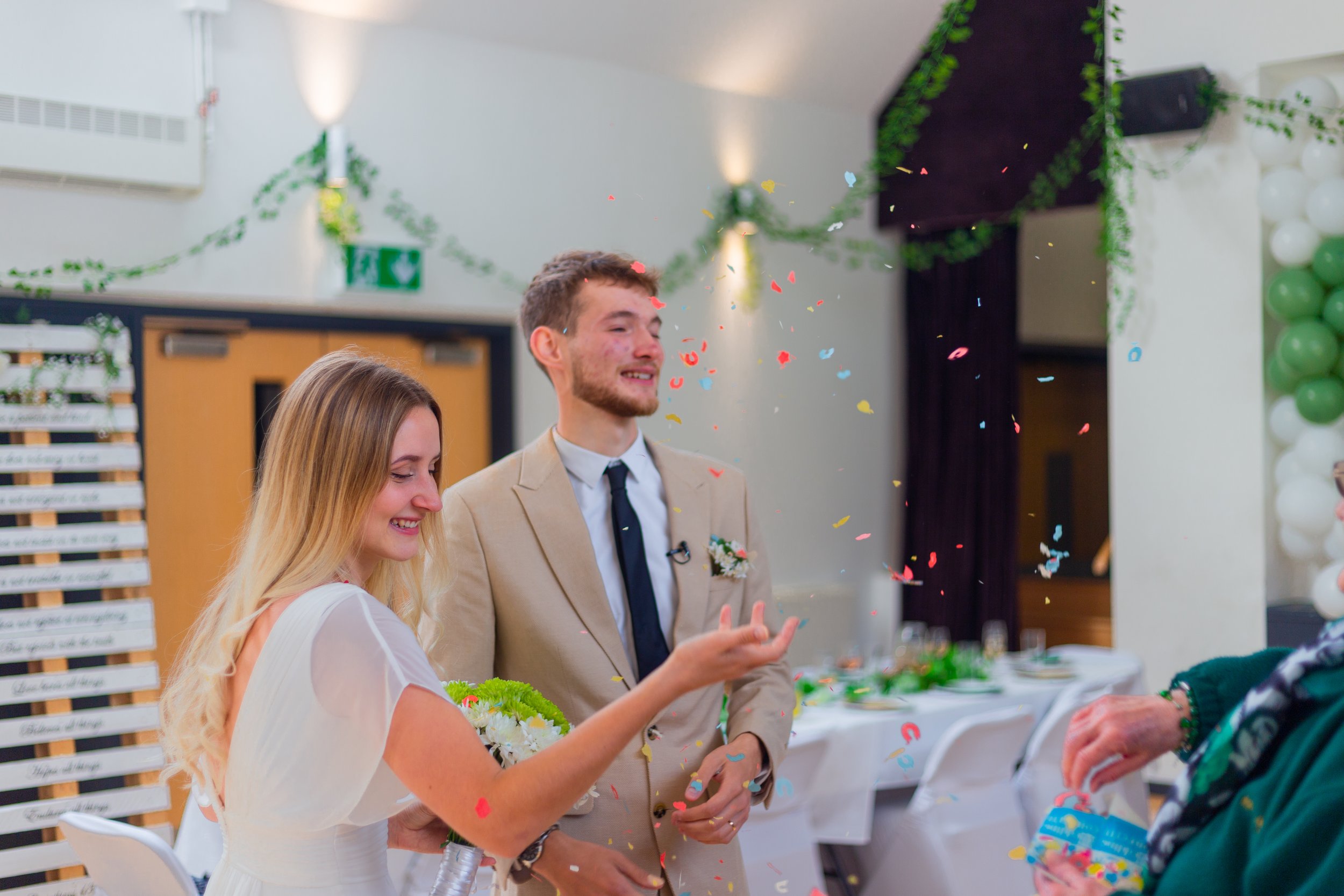 A wedding celebration with a bride and groom smiling as colorful confetti falls around them.