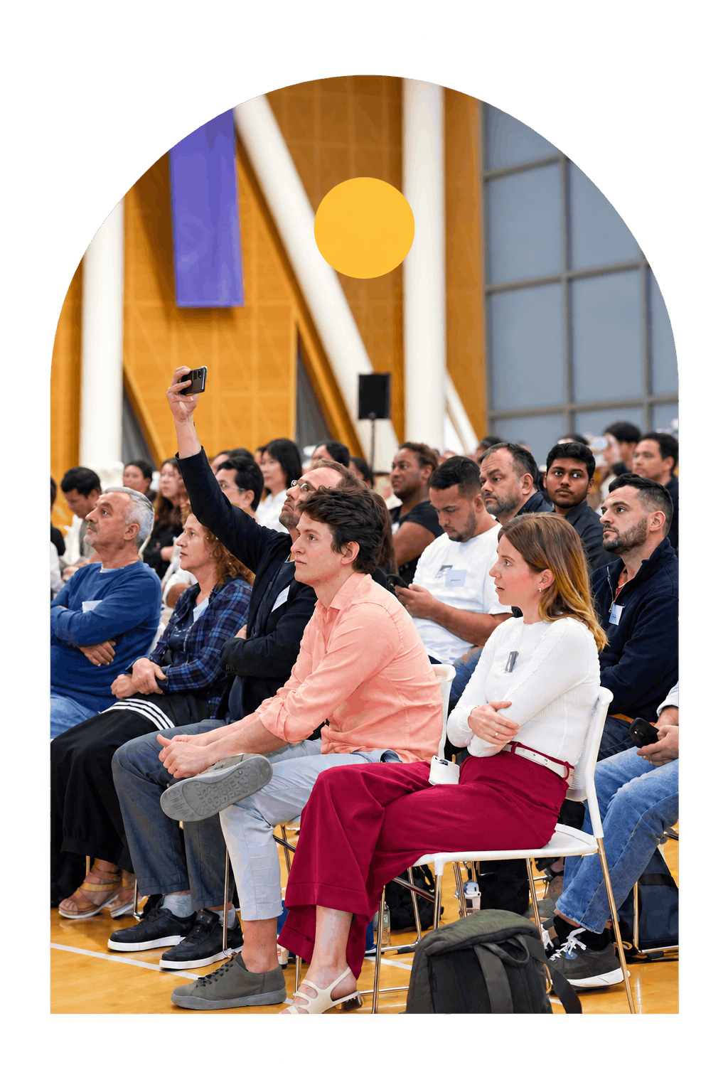 A diverse audience attentively listens during an indoor seminar, showcasing a collaborative learning environment.